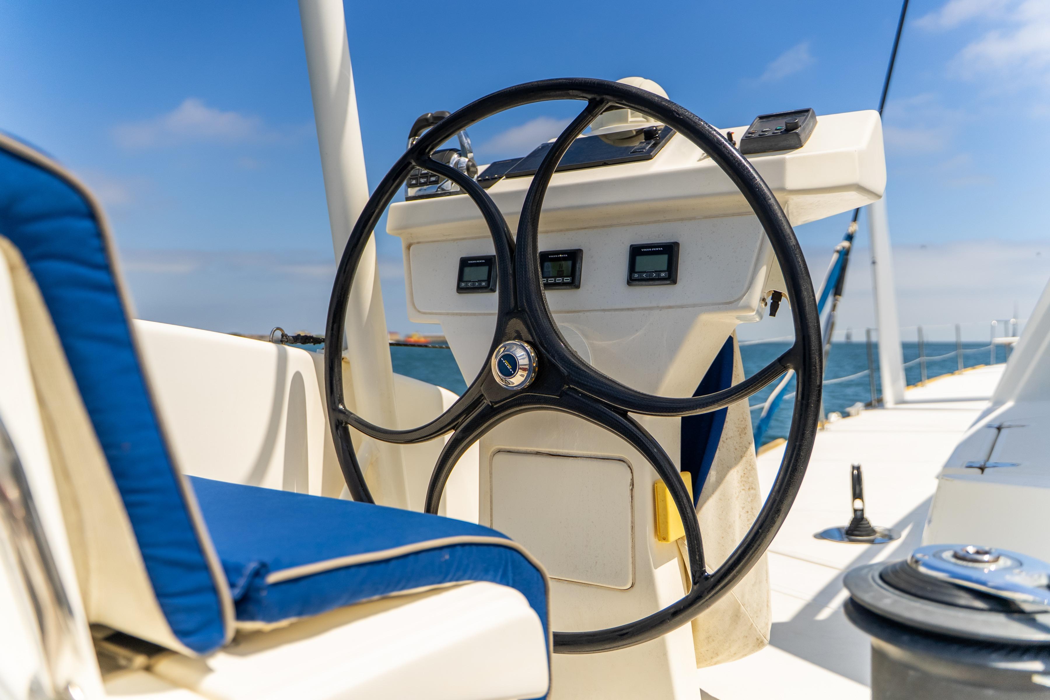 Steering wheel of a 2009 Catana 65 yacht with blue cushioned seating.