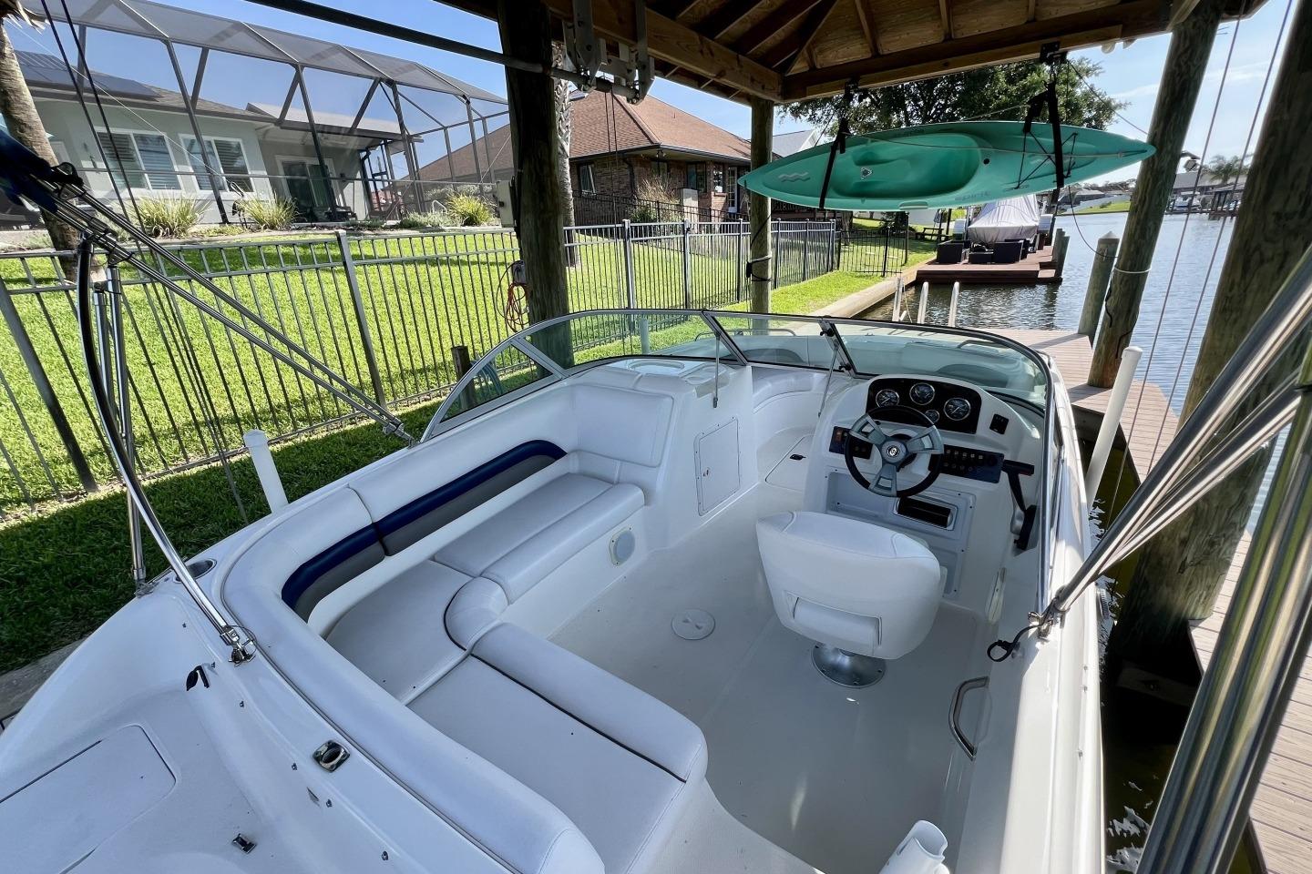 2013 Hurricane SunDeck 187 OB boat docked, featuring spacious seating and steering console.