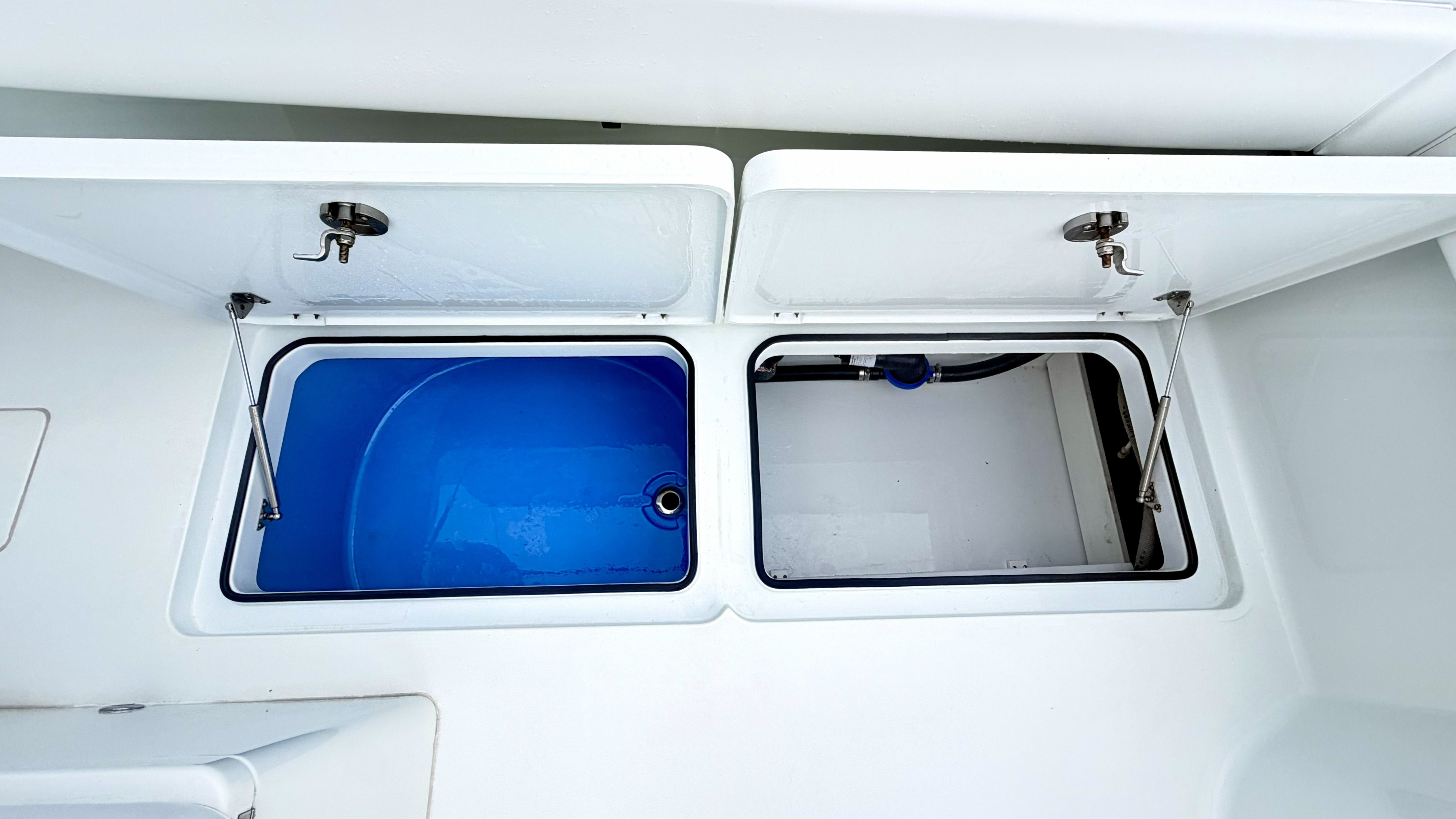 Two open storage compartments on a boat, one with a blue interior.