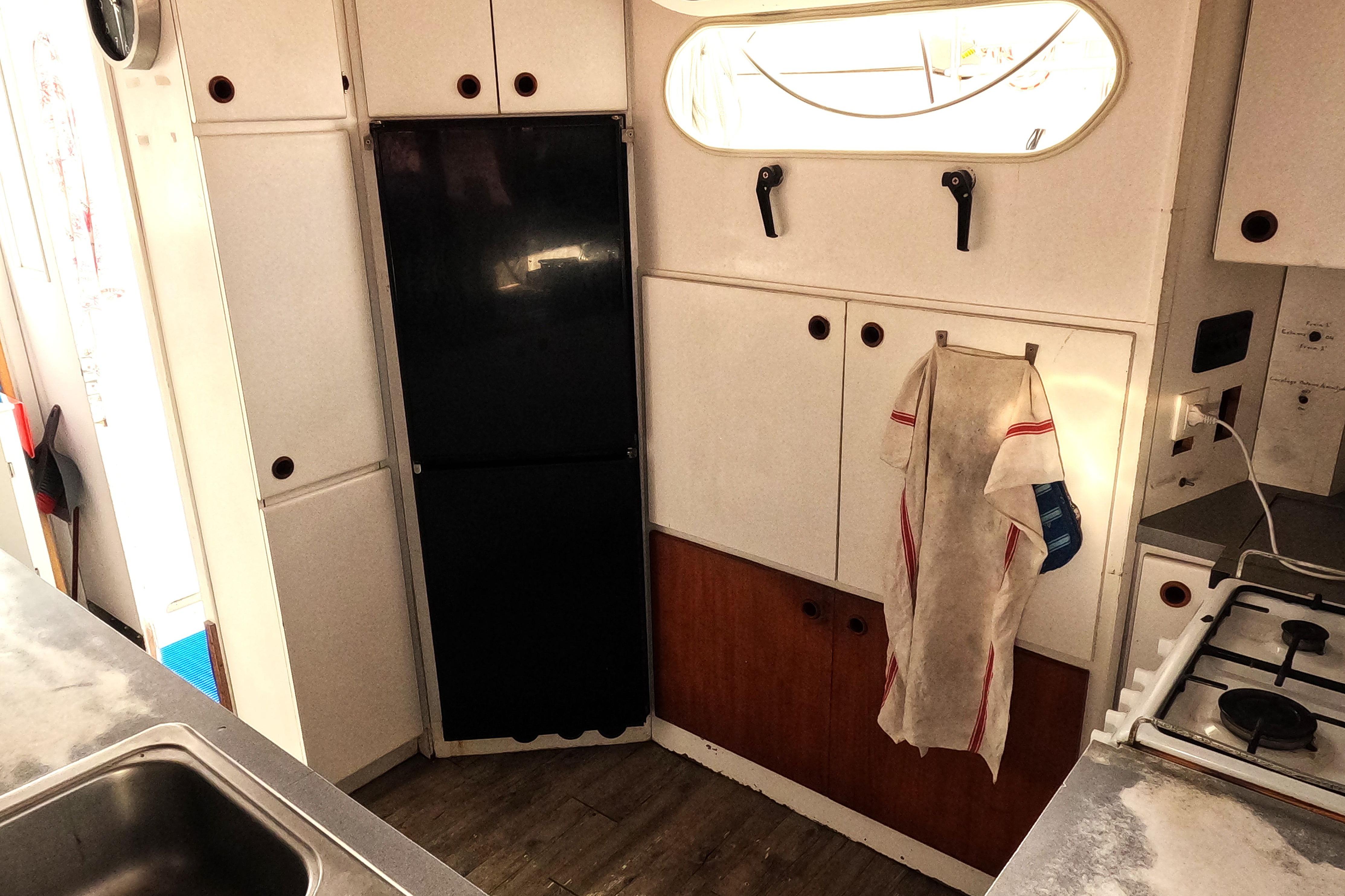 Interior of a 1996 Custom catamaran kitchen with cabinets, stove, and sink.