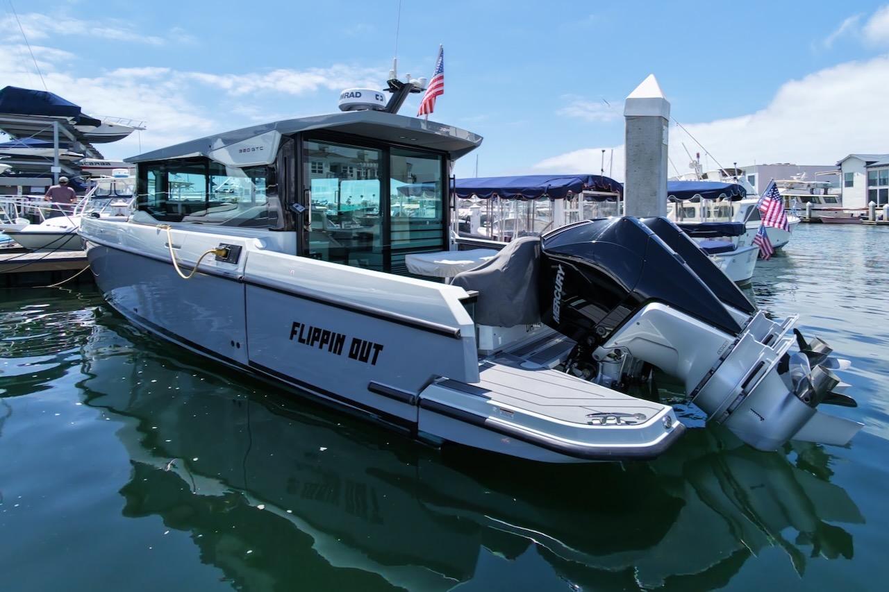 2024 Saxdor 320 GTC boat docked in marina, featuring sleek design and powerful outboard motor.