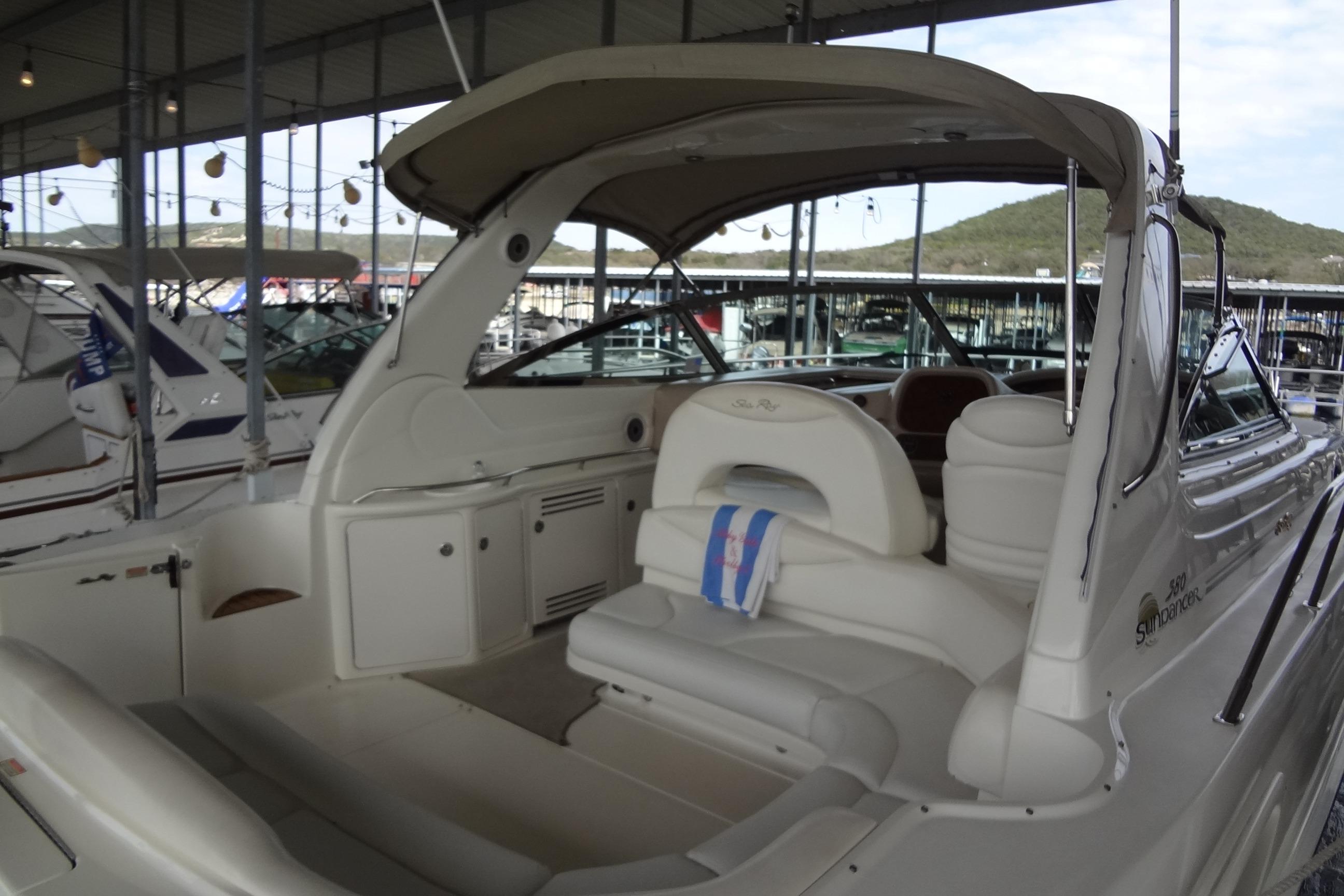 2001 Sea Ray 380 Sundancer yacht interior at marina, showcasing seating and helm area.