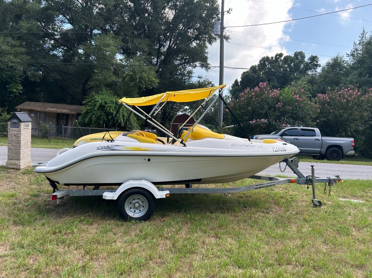 A white 2004 Sea-Doo Sportster LE DI boat on a trailer, parked on grass.