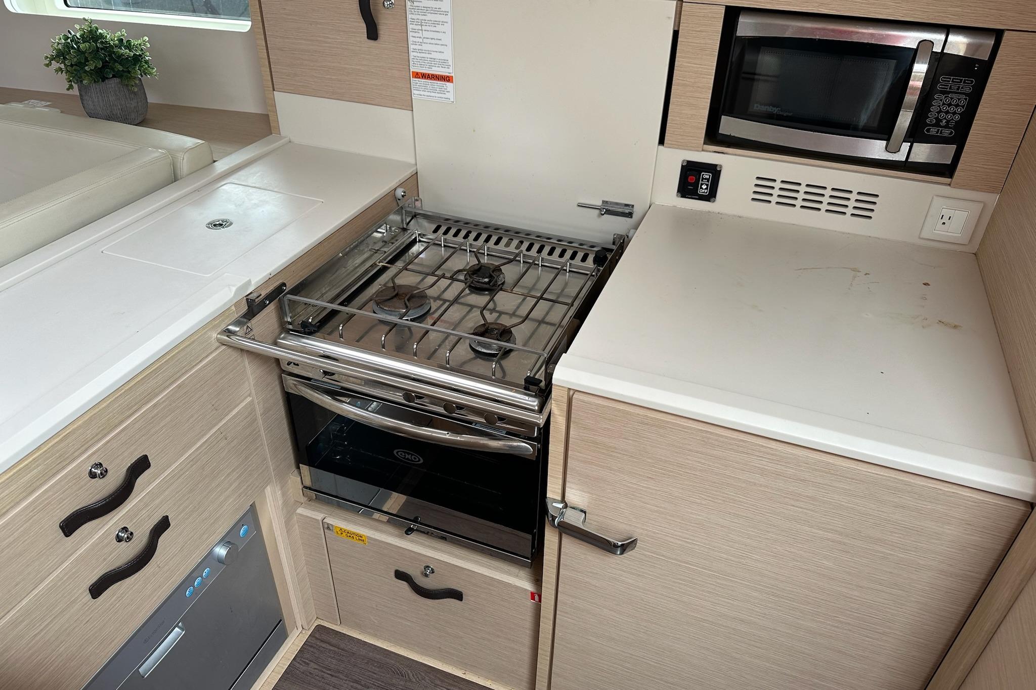 Modern kitchen area in a 2018 Jeanneau 51 yacht with stove and microwave.