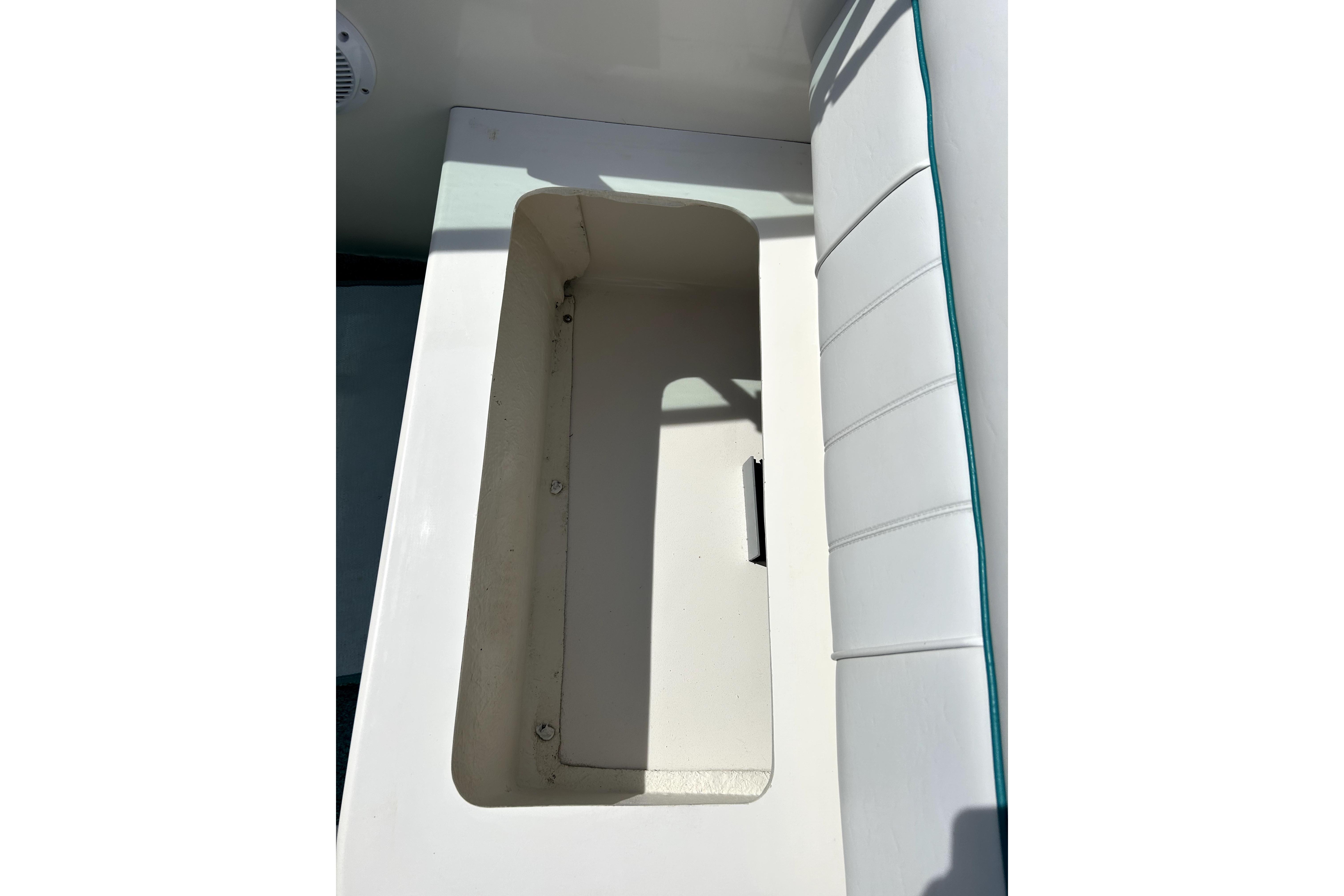 Open storage compartment on 1995 Sea Ray 250 Sundancer boat with white seating.