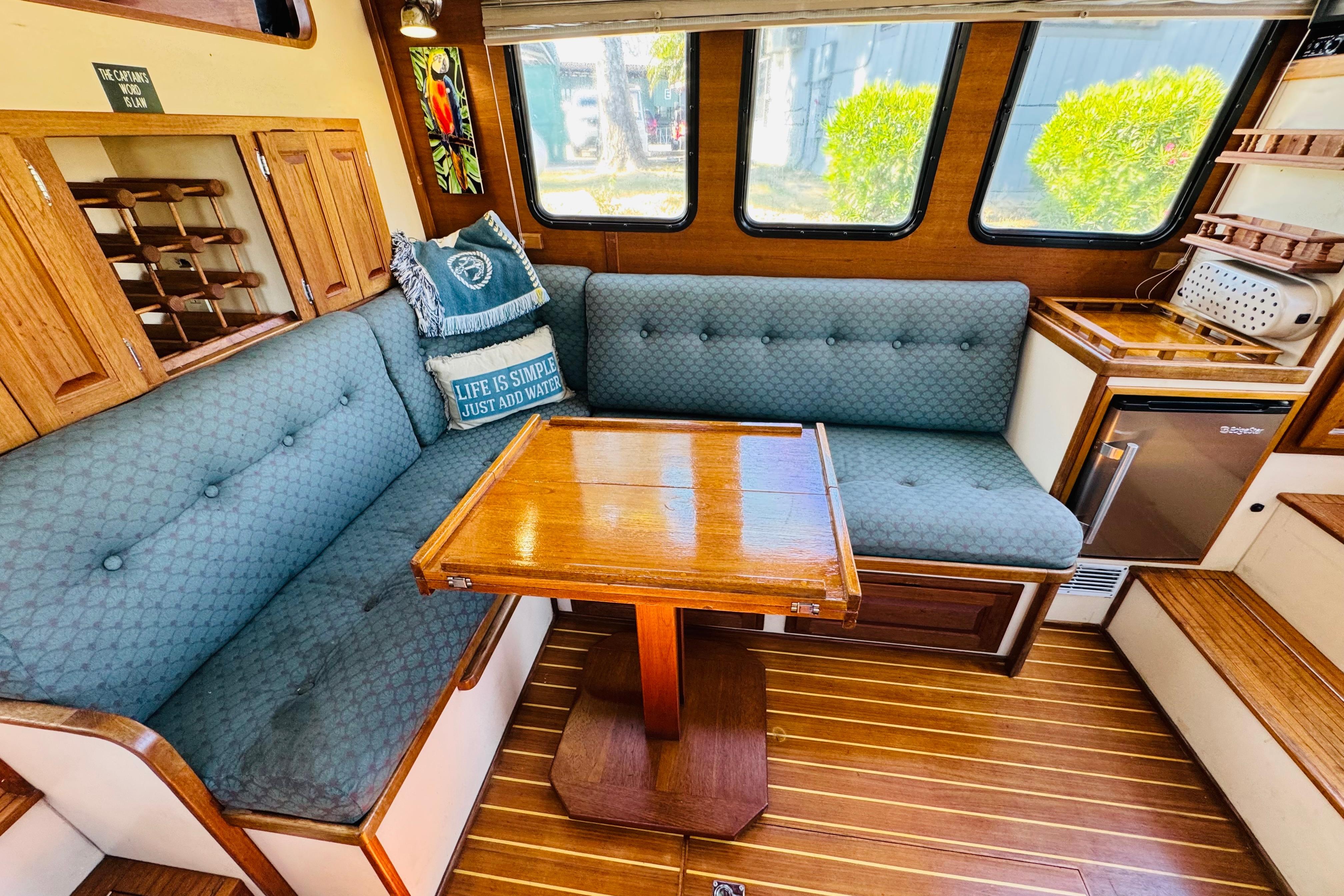 Cozy interior of a 1996 Nordic Tug 32 with wooden table and cushioned seating.