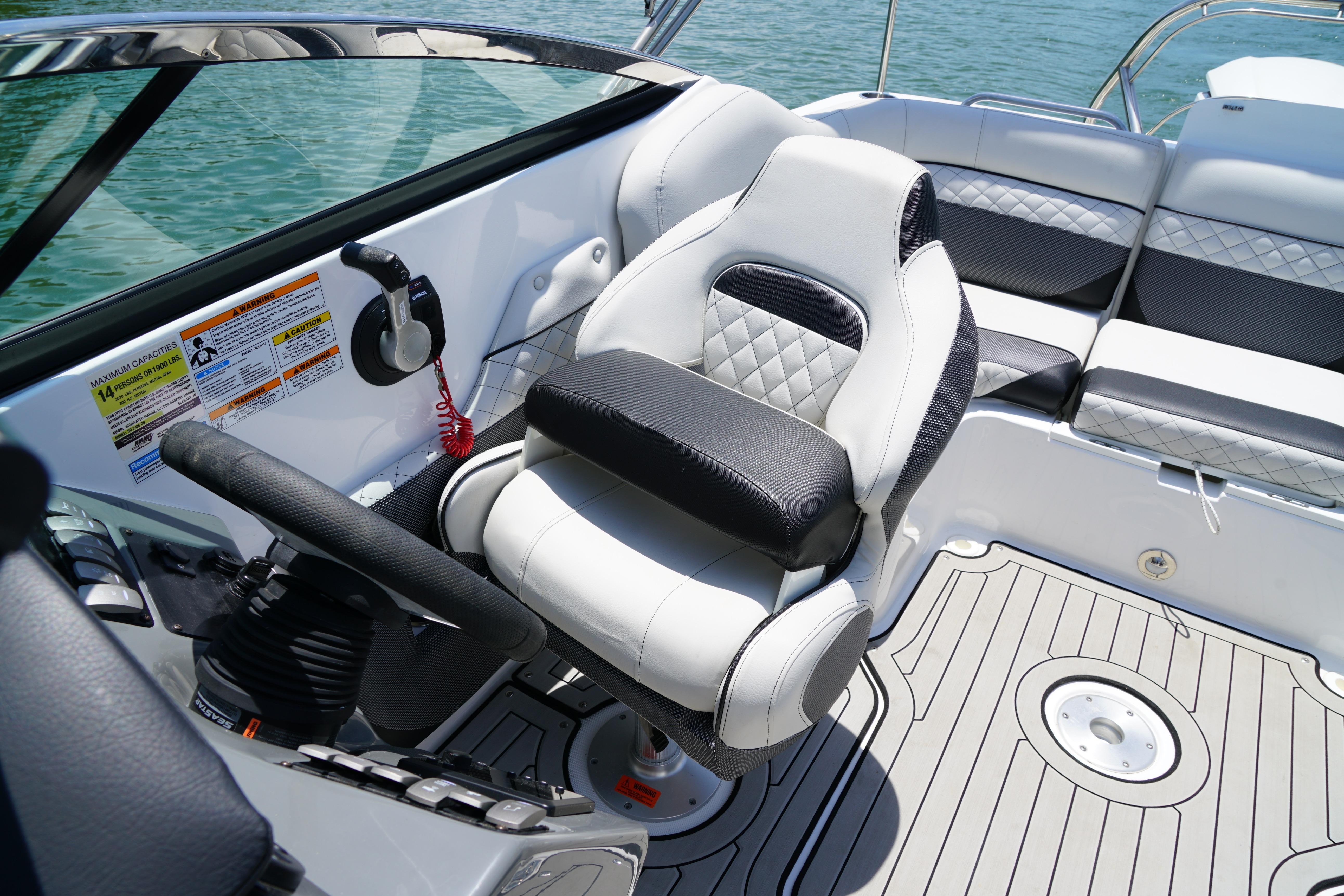 2020 Hurricane SunDeck 2486 OB boat interior with steering wheel and cushioned seating.