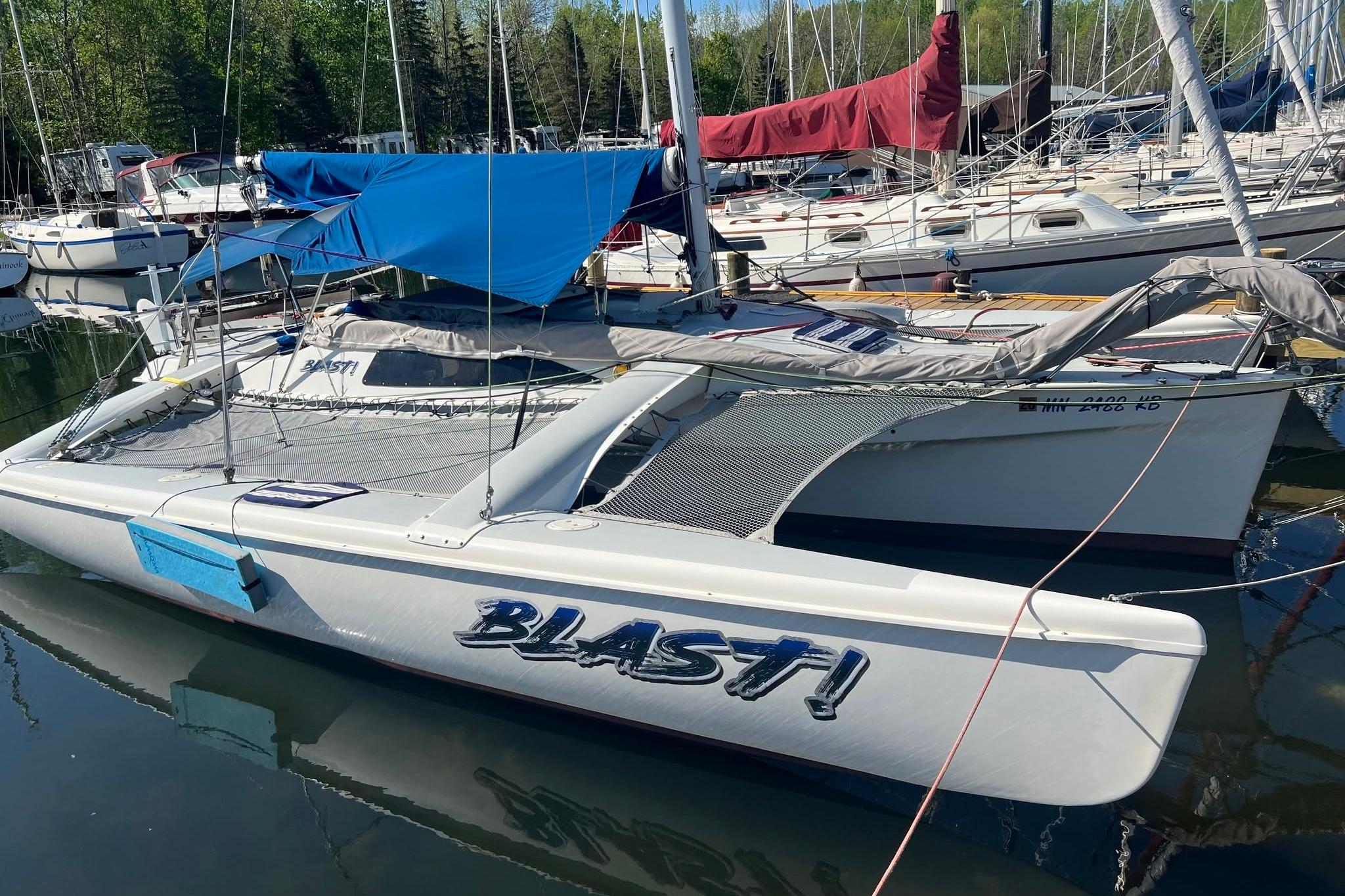 1993 Corsair F-27 trimaran named "BLAST!" docked among other sailboats.