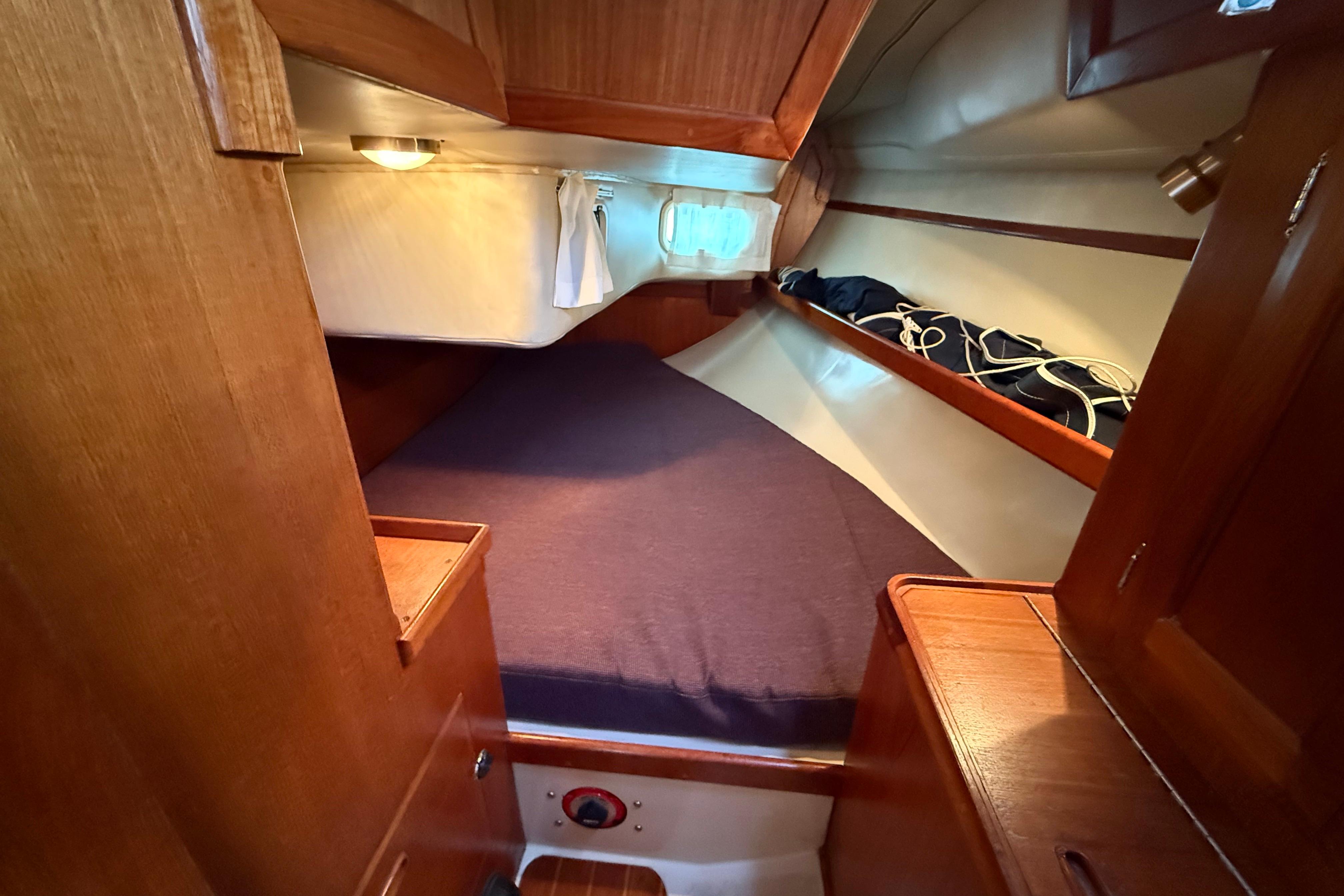 Cozy cabin interior of 1988 Ericson 32-200 sailboat with wooden finish and bedding.