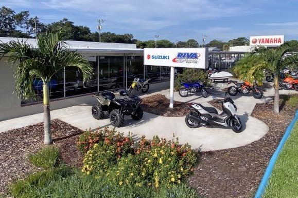 Outdoor display of Yamaha and Suzuki vehicles at Riva Motorsports dealership, featuring motorcycles and ATVs.