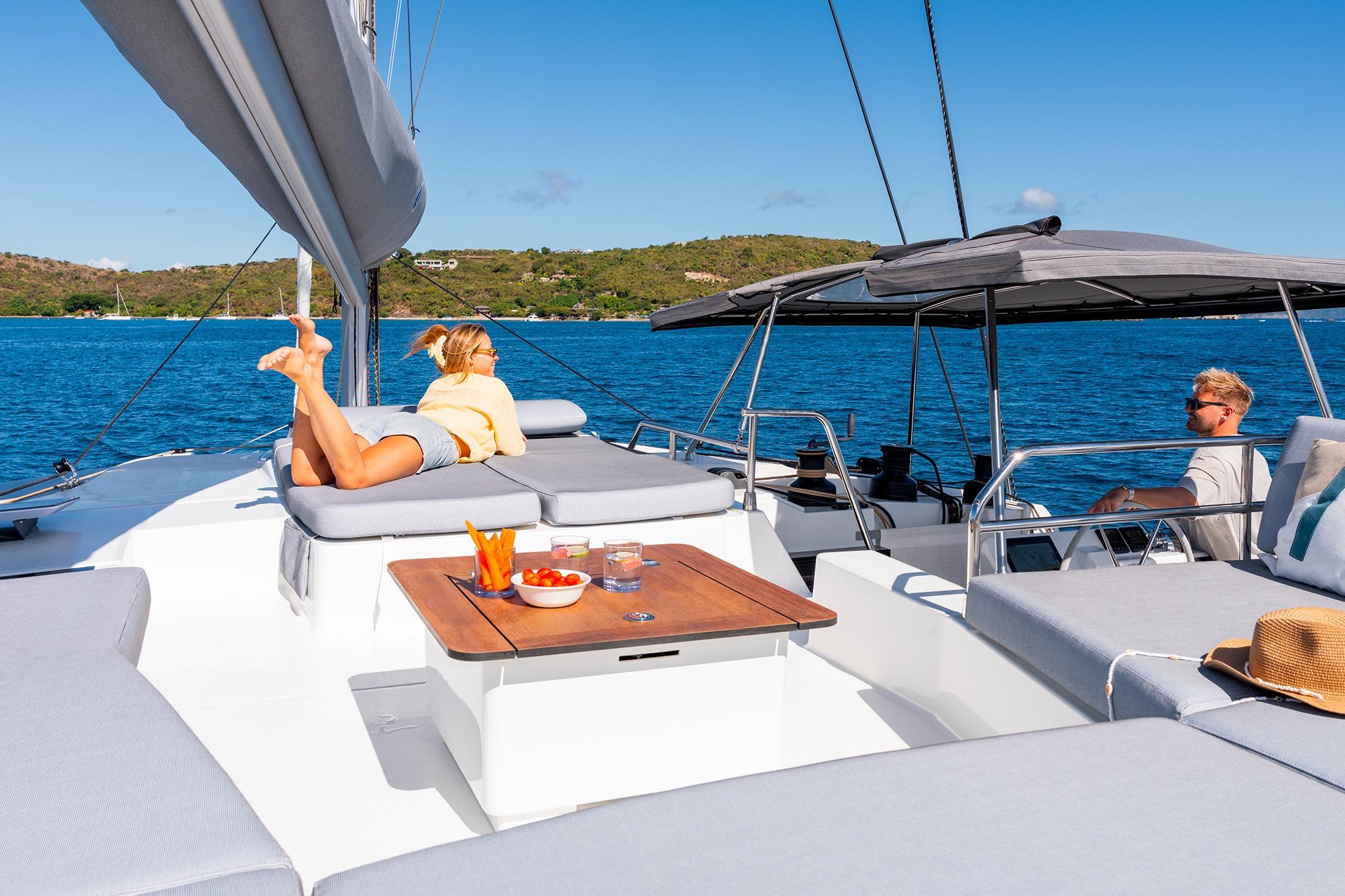 2026 Fountaine Pajot Aura 51 Catamaran with people relaxing on deck in sunny weather.