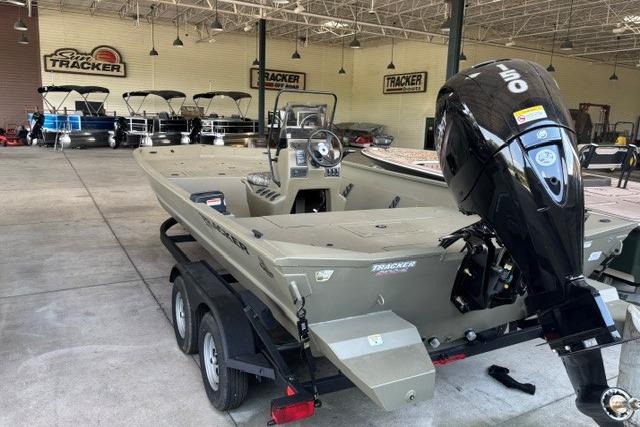 2026 Tracker Grizzly 2072 CC boat with outboard motor in showroom.