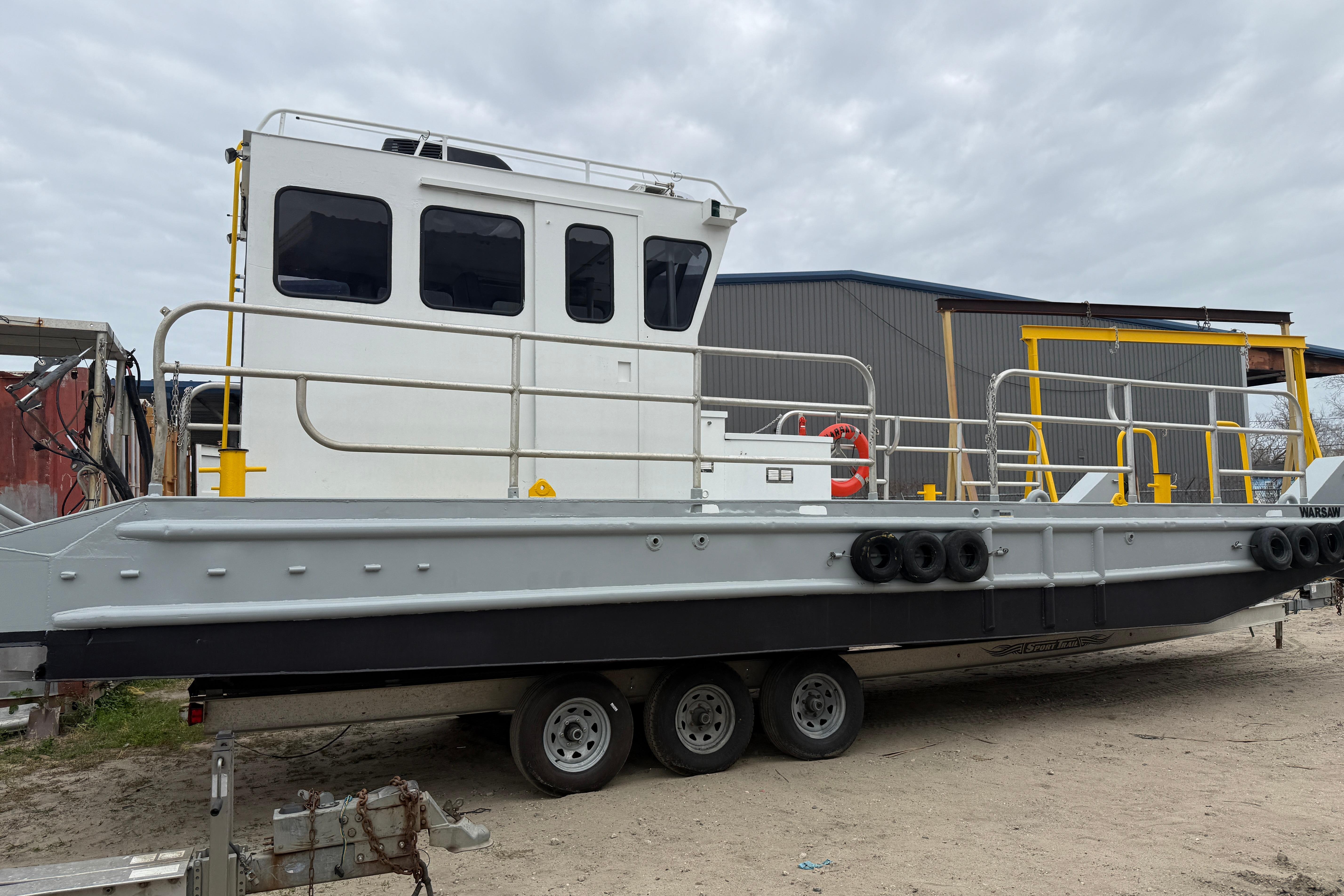 Custom Aluminum Work Boat 34x10, 2010 model, on trailer, docked outdoors.