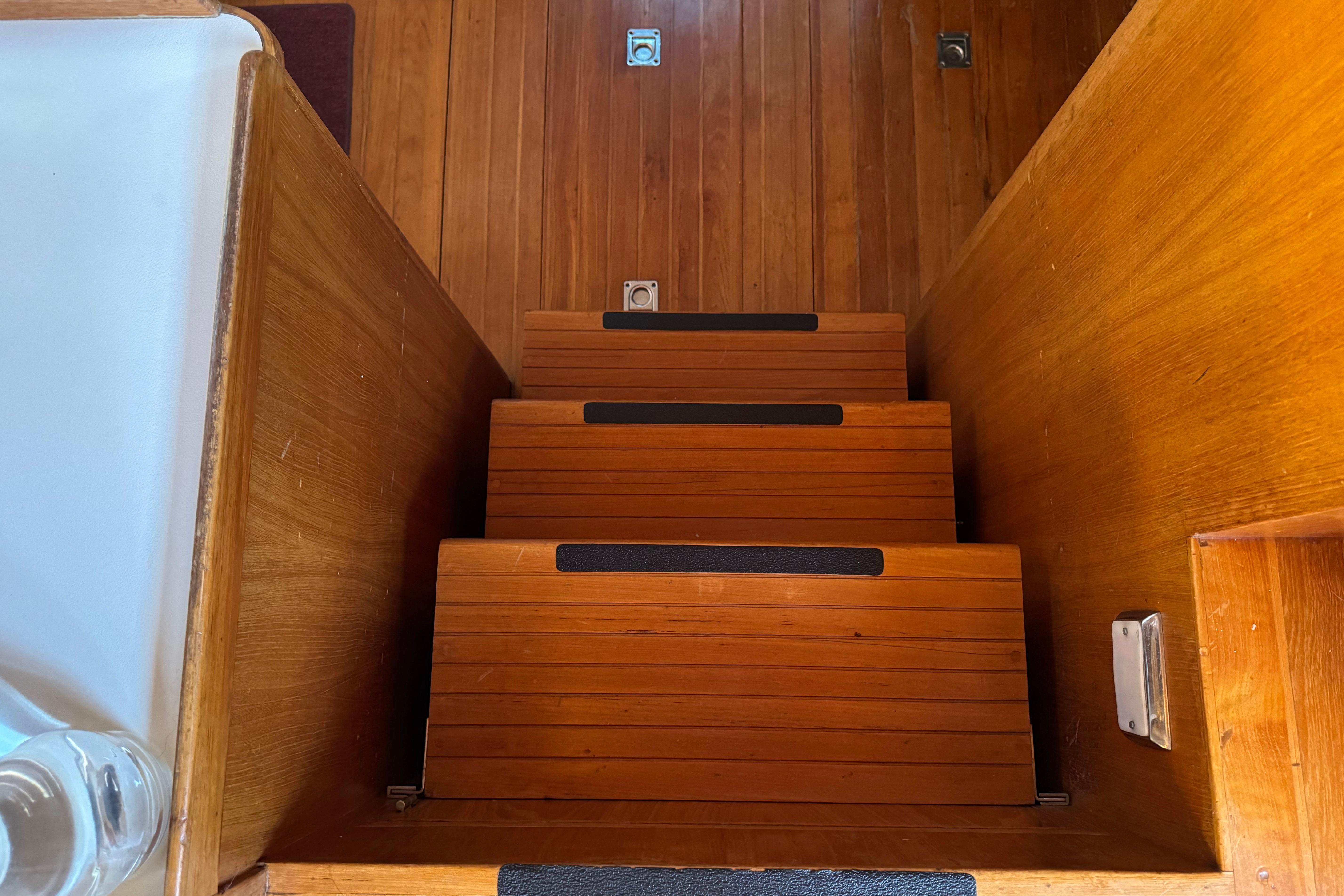 Wooden stairs inside a 1987 President 37 yacht, featuring sleek design and warm tones.