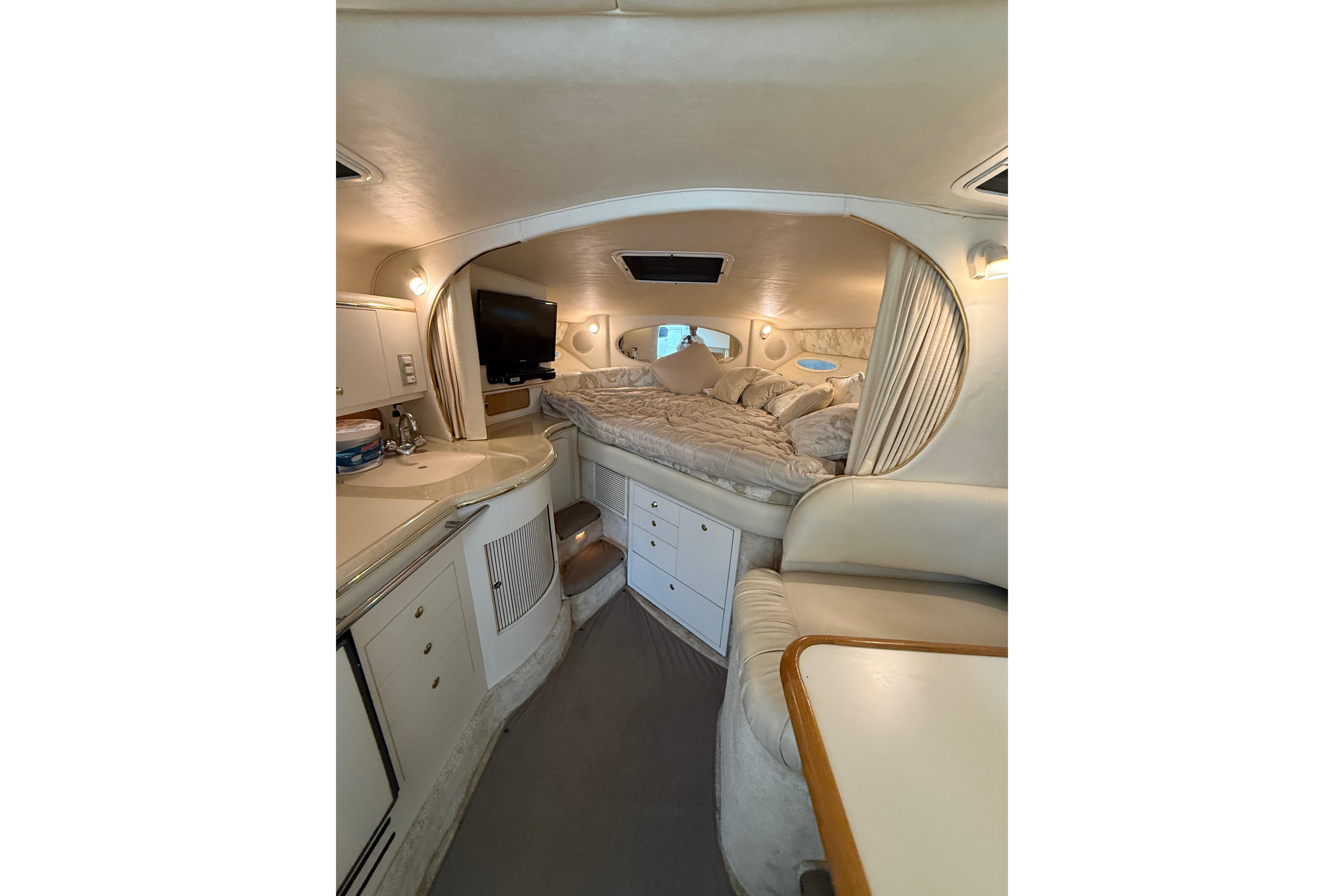 1999 Sea Ray Sundancer 310 cabin interior with bed, TV, and kitchenette.