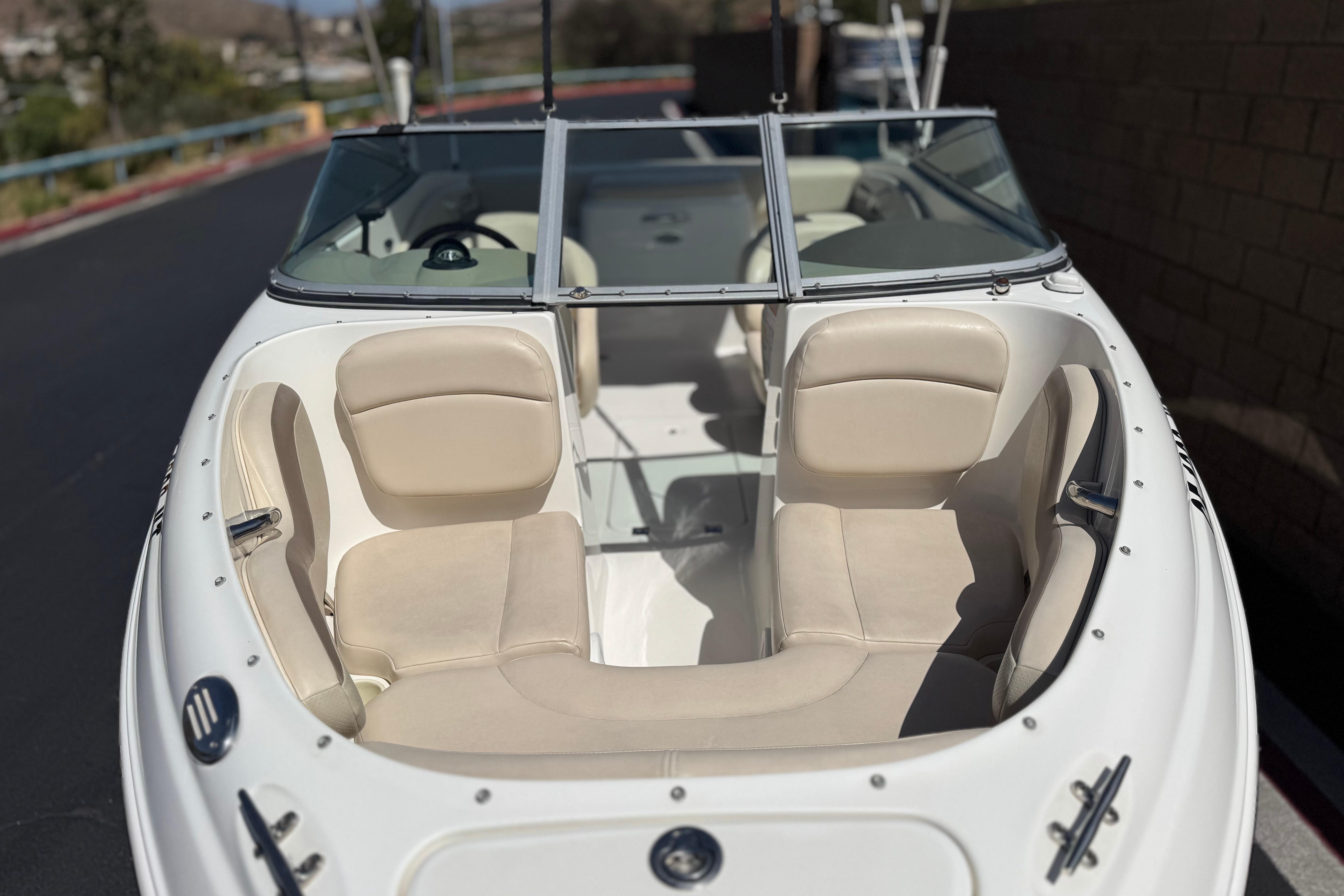 2006 Chaparral 190 SSi boat with beige seating and windshield, parked outdoors.