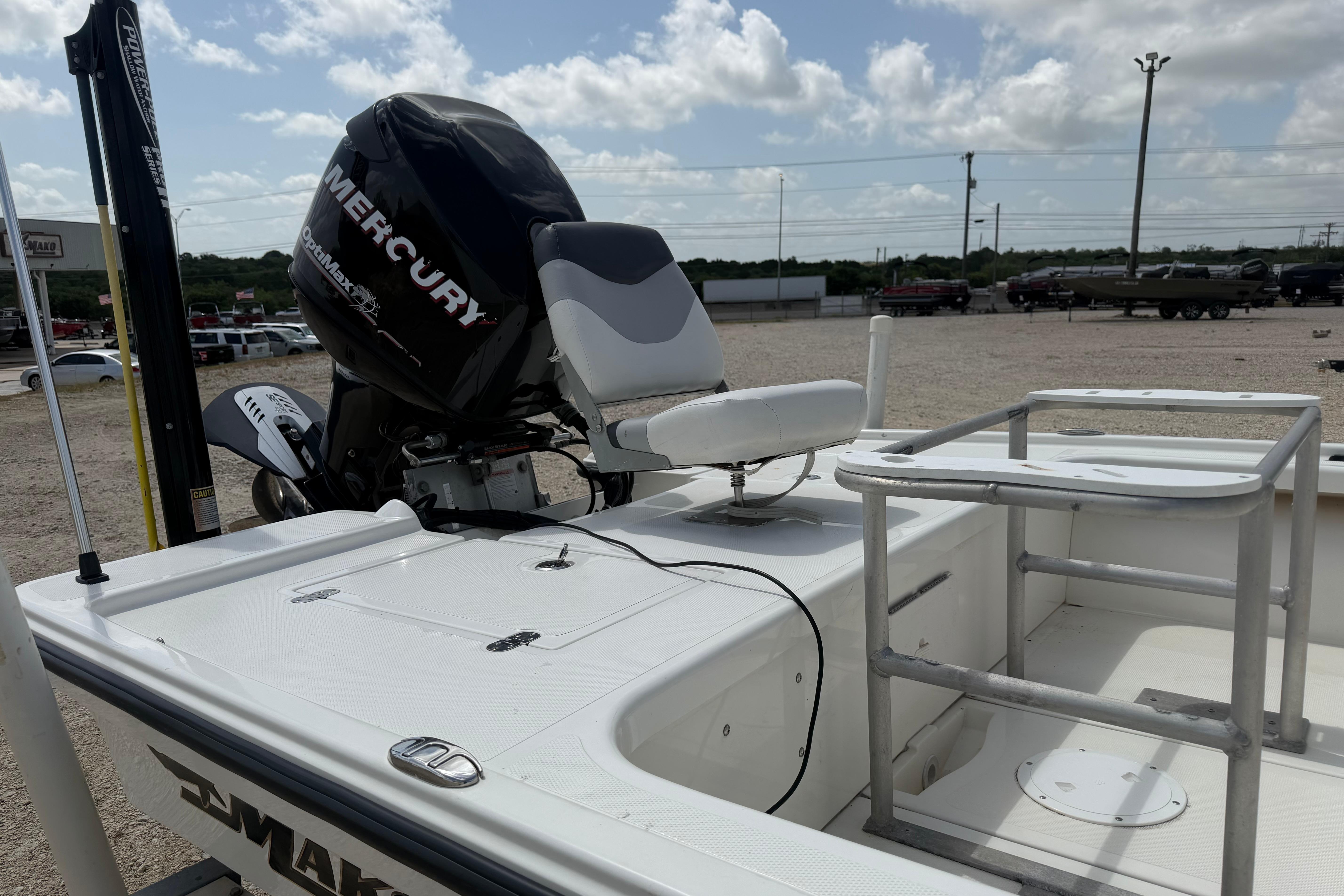 2012 Mako 18 LTS boat with Mercury outboard motor, docked under a cloudy sky.