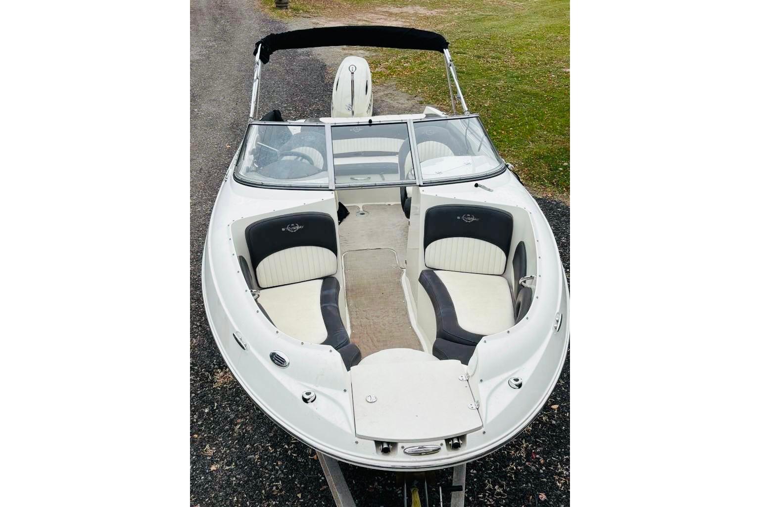 2018 Stingray 214 LR boat with white and black seating, parked on gravel.