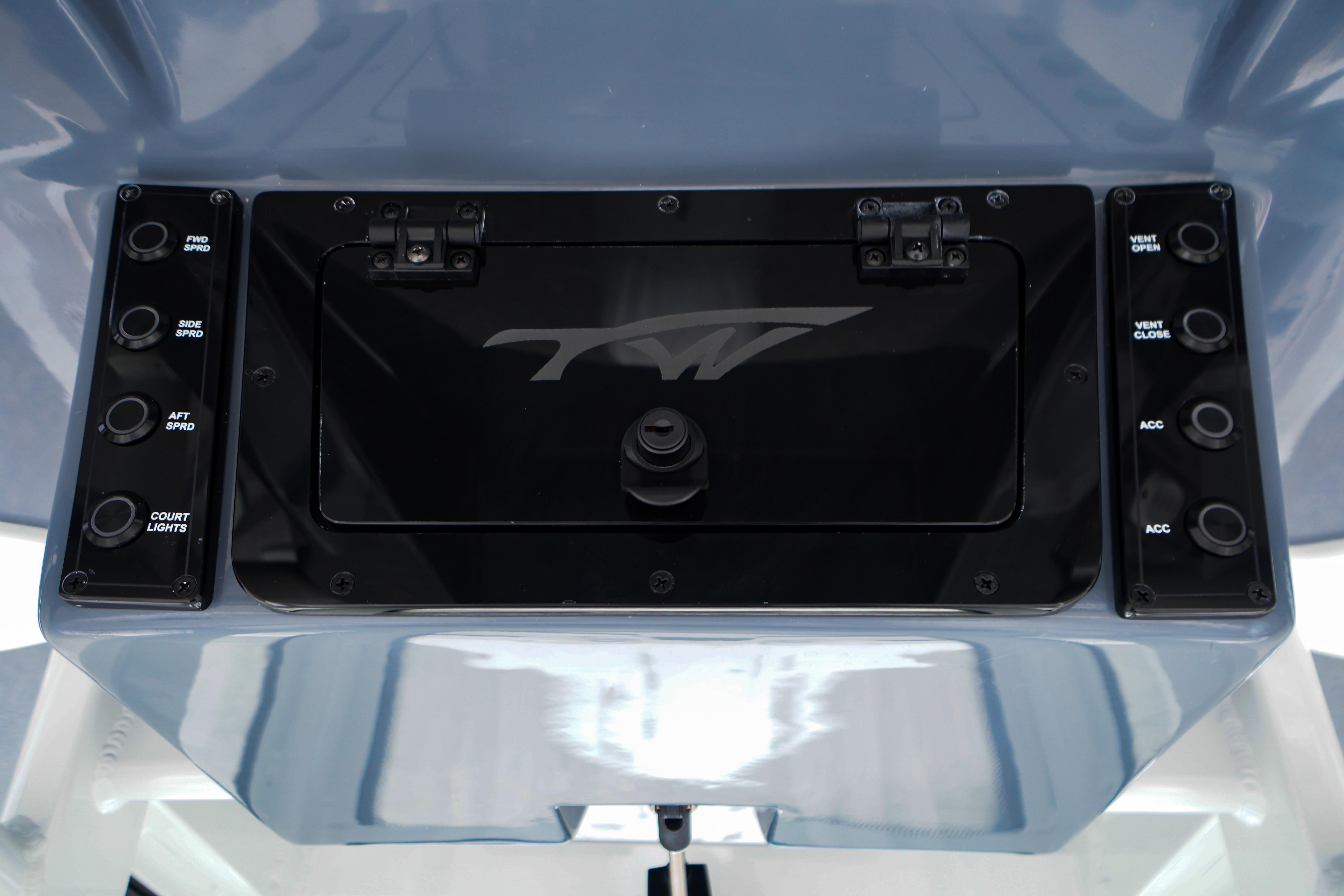 Control panel of 2026 Tidewater 232 SS boat with labeled switches and storage compartment.