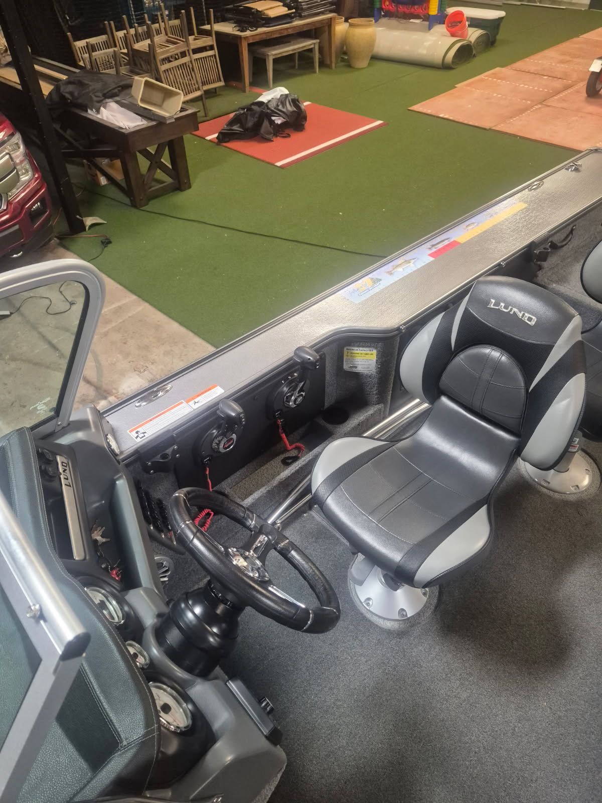 The image shows the cockpit of a Lund Pro-V 2075 boat with a padded seat and steering.