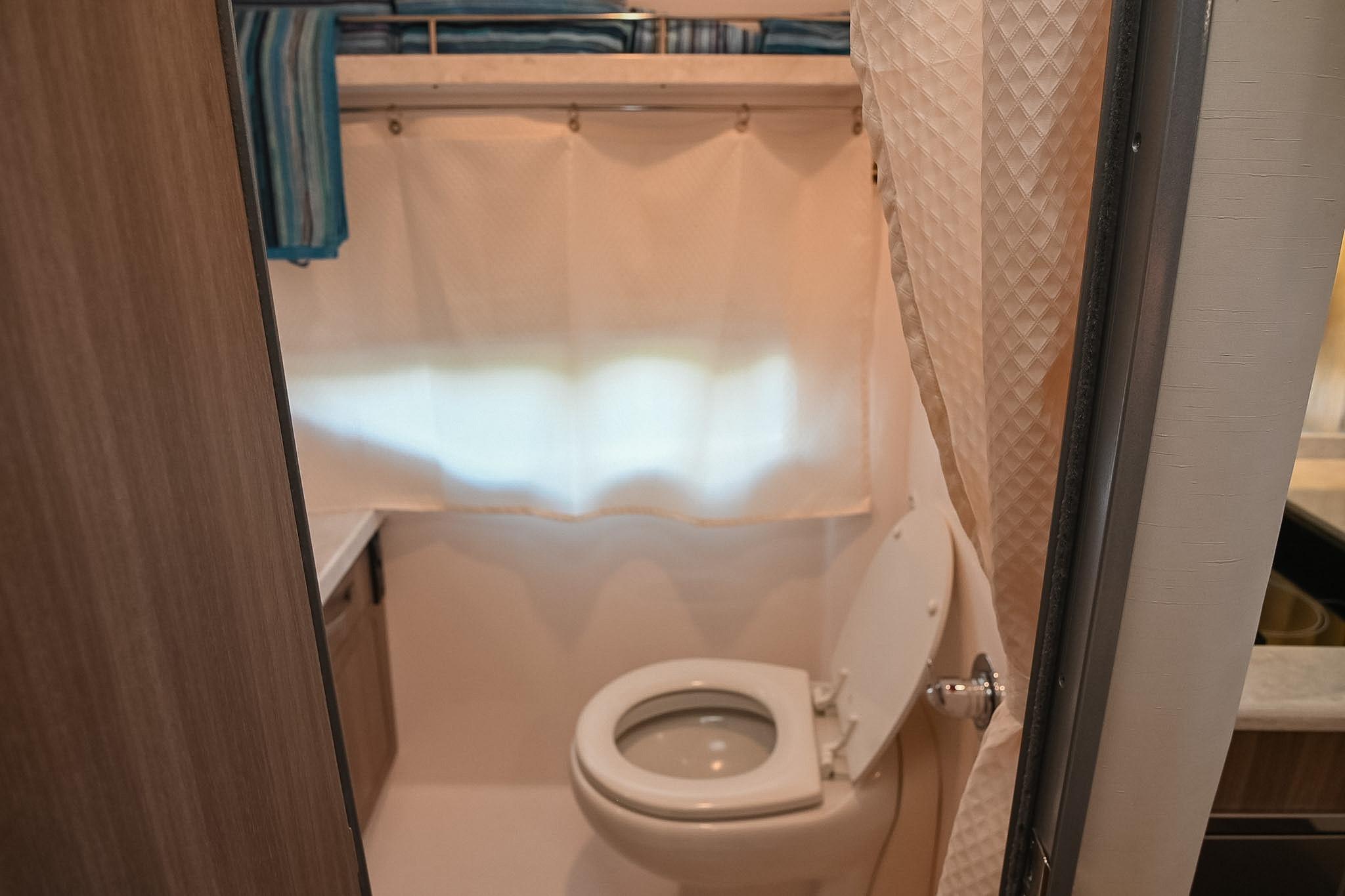 Bathroom interior of 2021 Regal 33 Express boat with toilet and shower curtain.