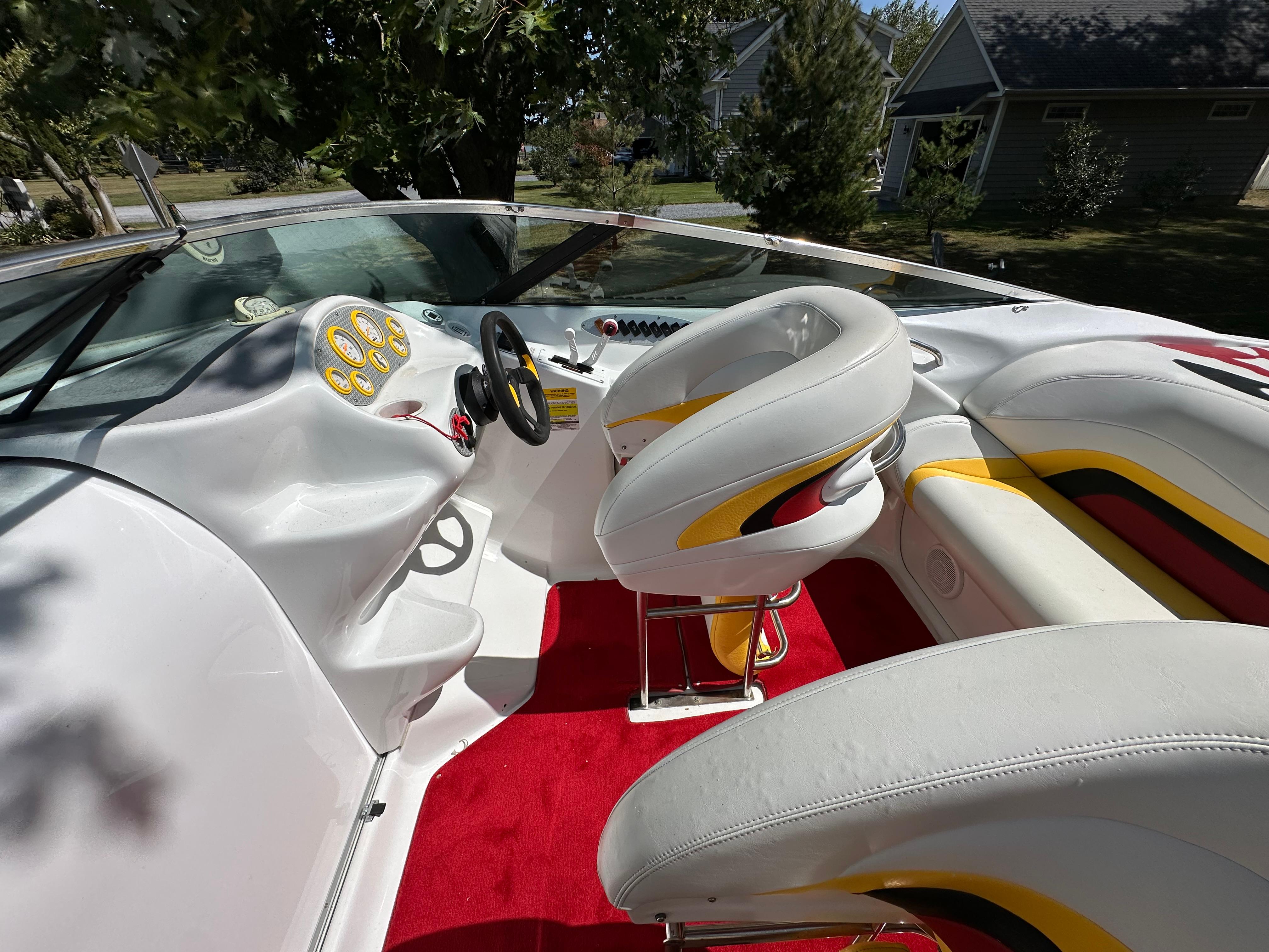 2001 Baja 232 boat interior with white seats, red carpet, and dashboard controls.