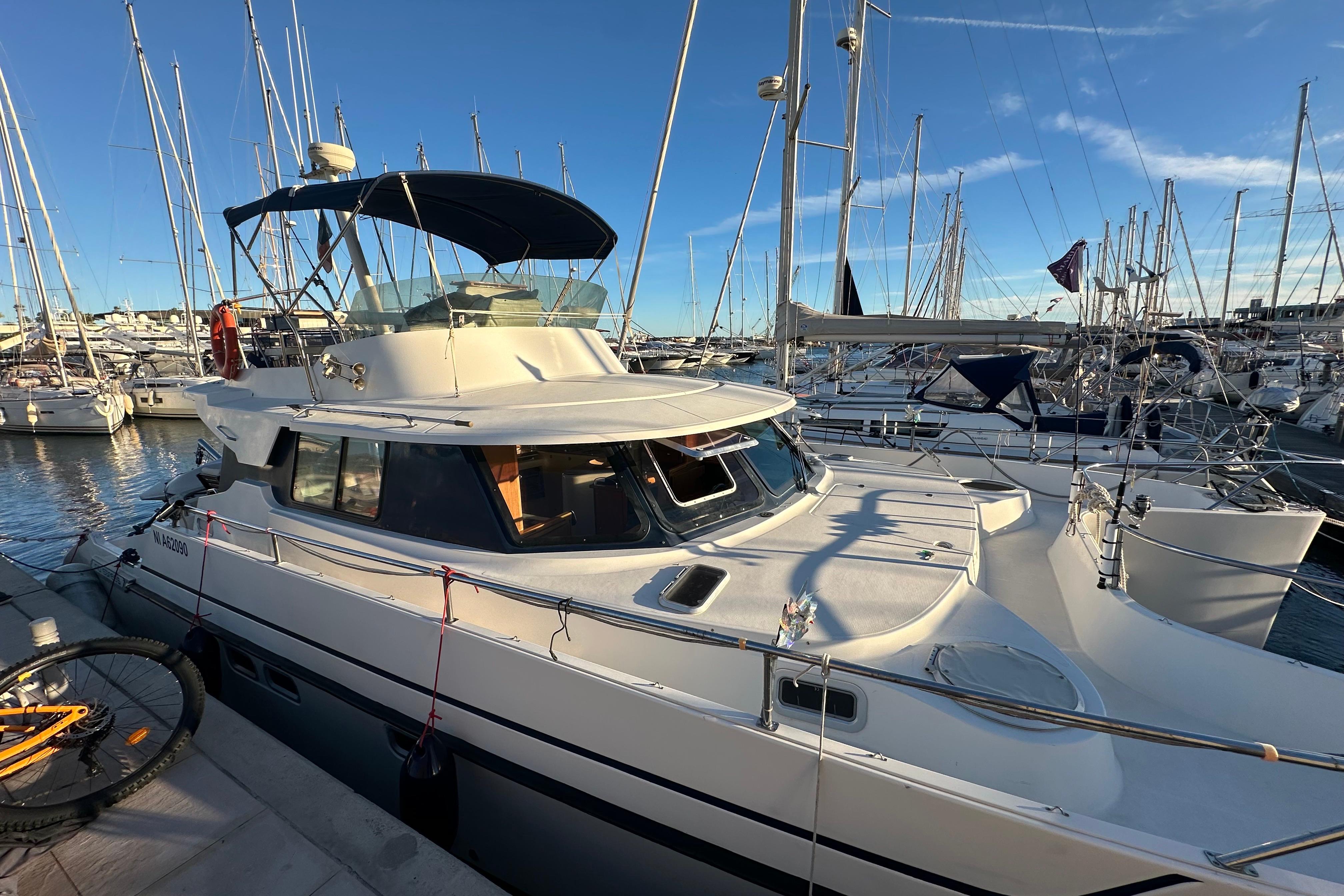 1999 Fountaine Pajot Maryland 37 yacht docked in a marina under clear blue skies.