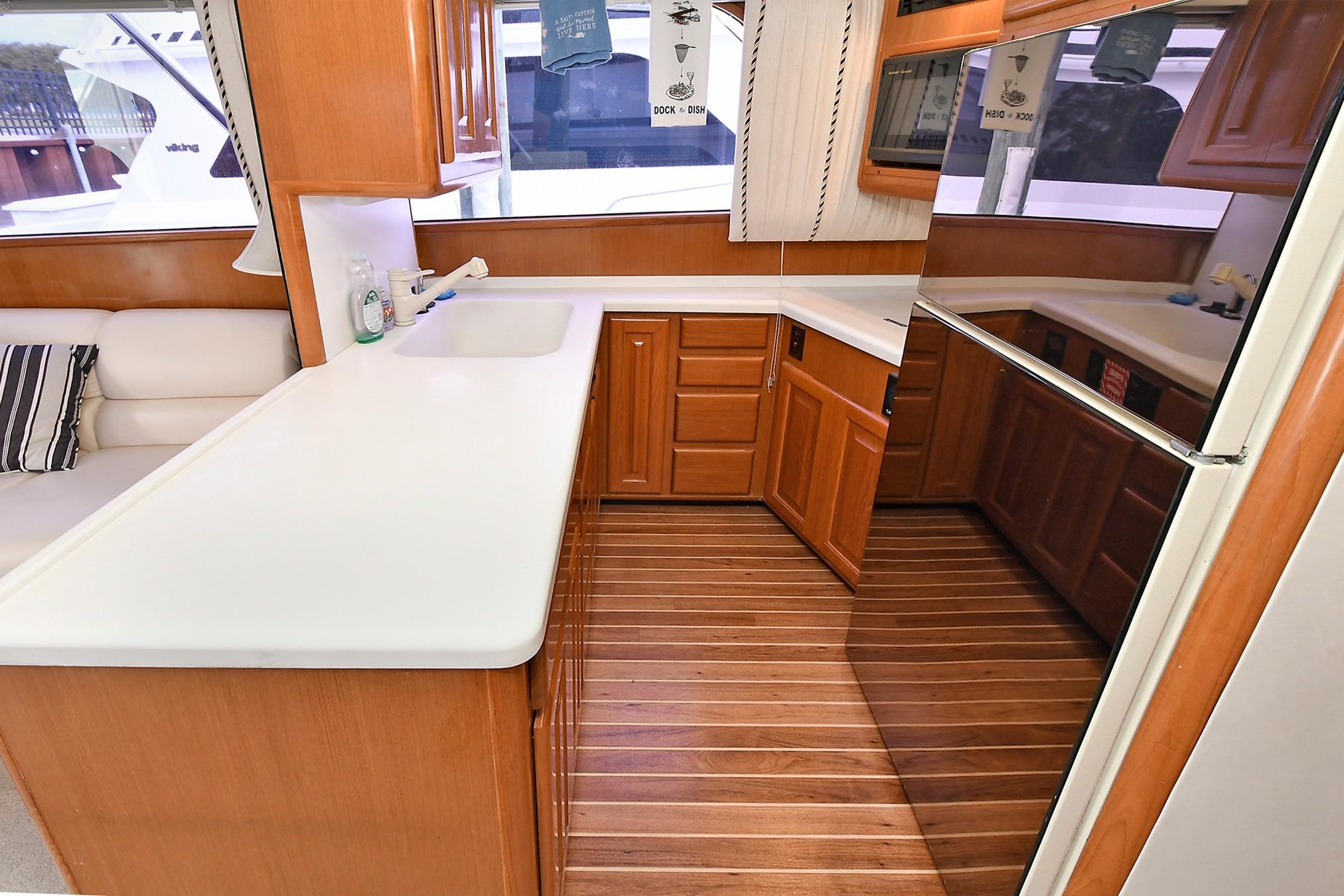 Spacious kitchen area in a 1997 Viking 47 Convertible yacht with wooden cabinetry.