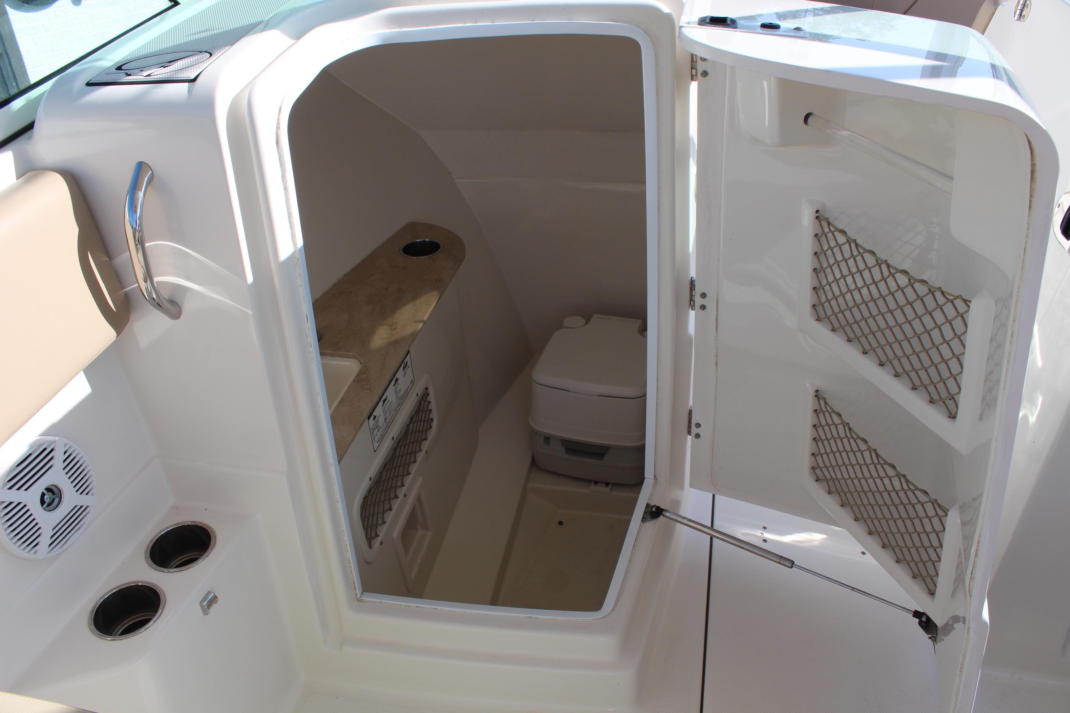 2017 Sailfish 275 DC boat interior with open storage compartment and portable toilet.
