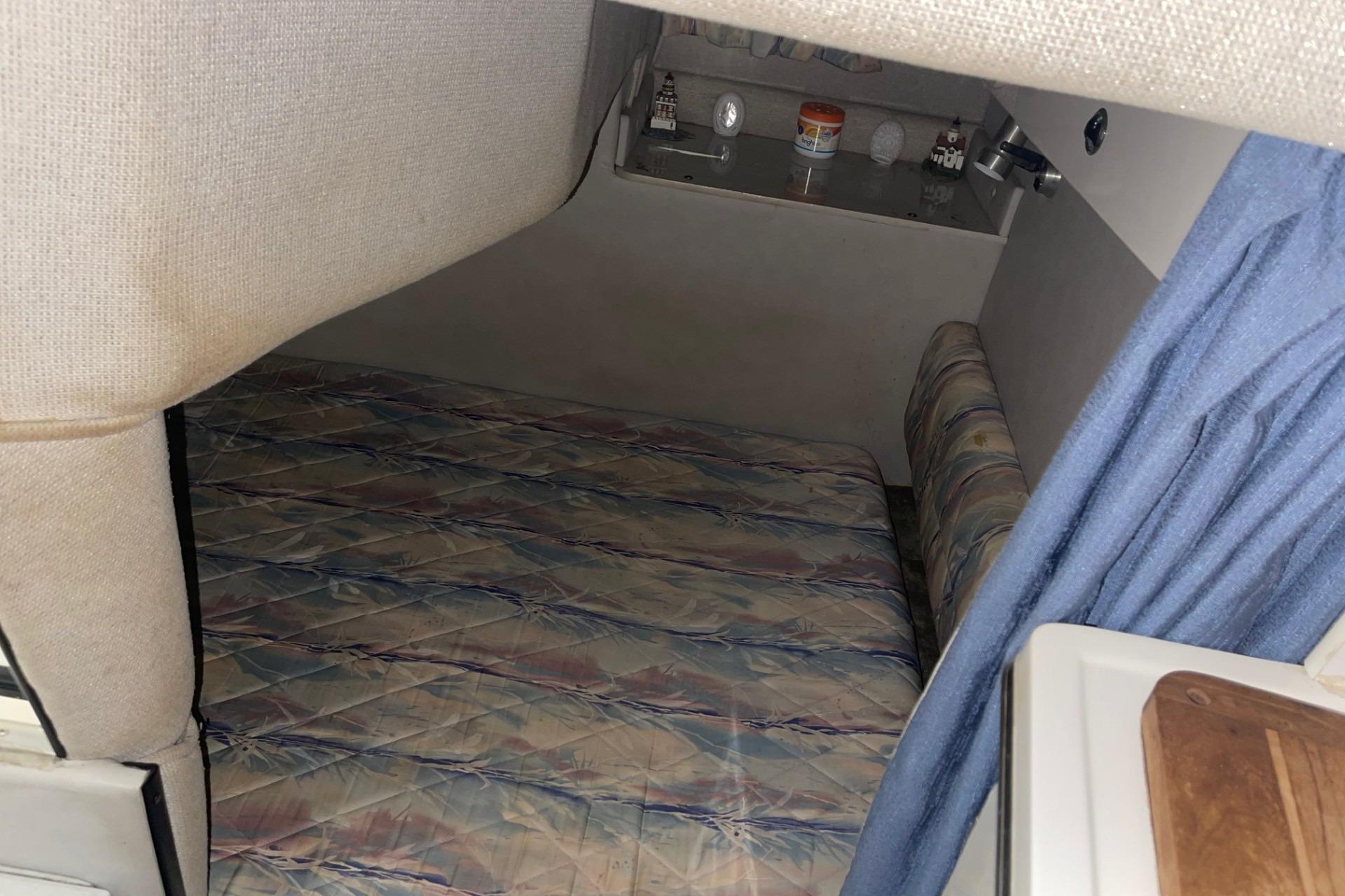 1992 Chaparral Signature 30 cabin interior with bed, blue curtain, and storage shelf.