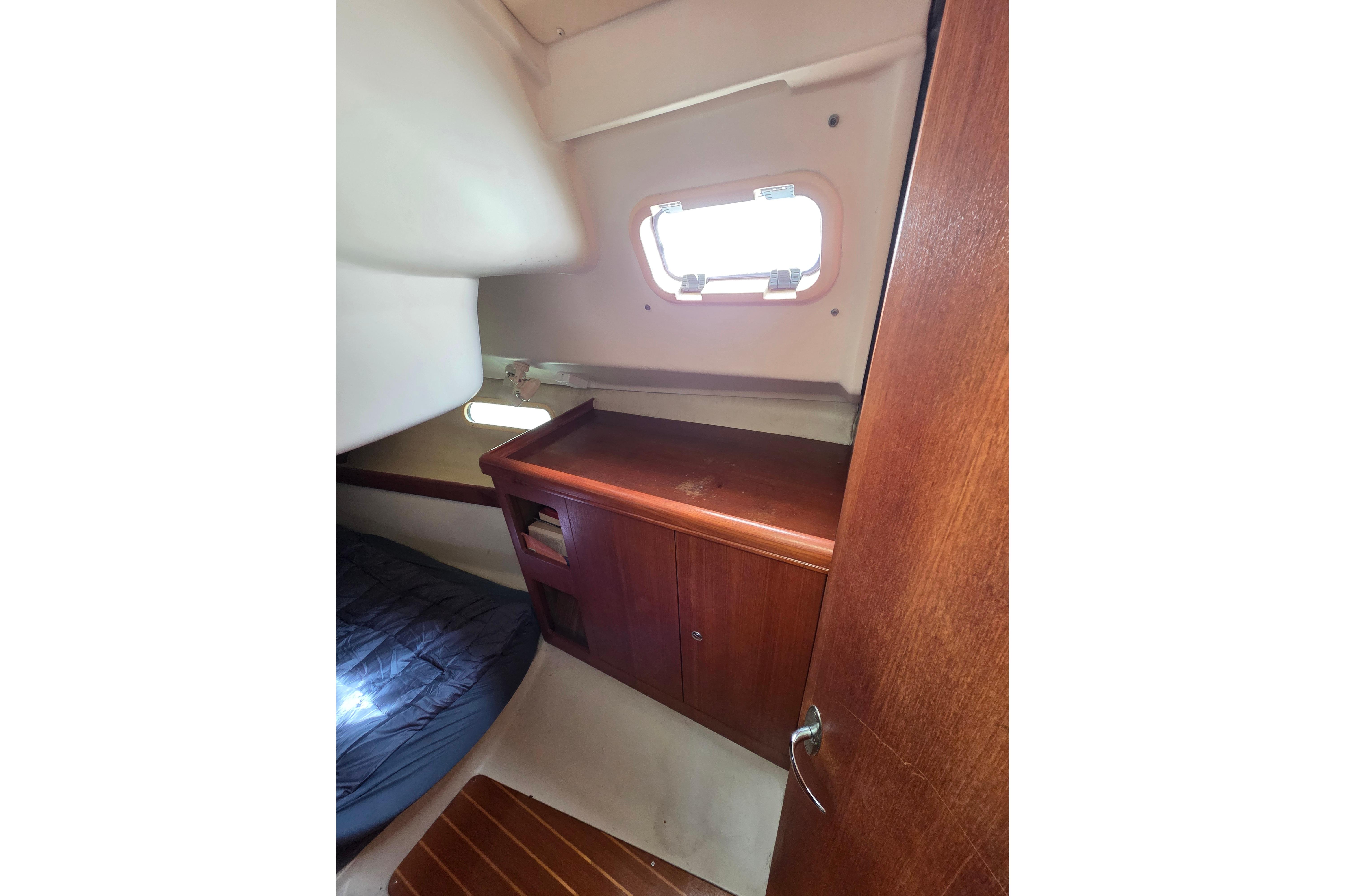 2003 Hunter 326 yacht cabin interior with wooden cabinetry and small window.
