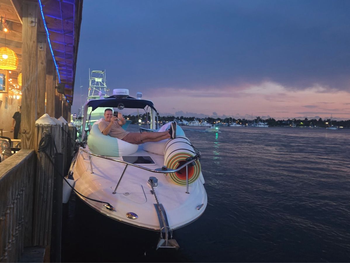 A man relaxes on a boat docked at a pier during sunset.