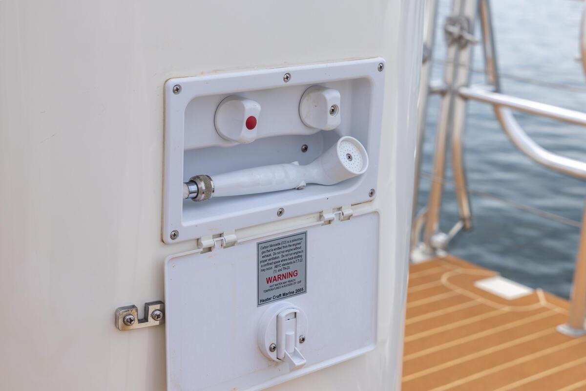 Outdoor shower on 2023 ArrowCat 420 Flybridge yacht, with teak deck and ocean view.