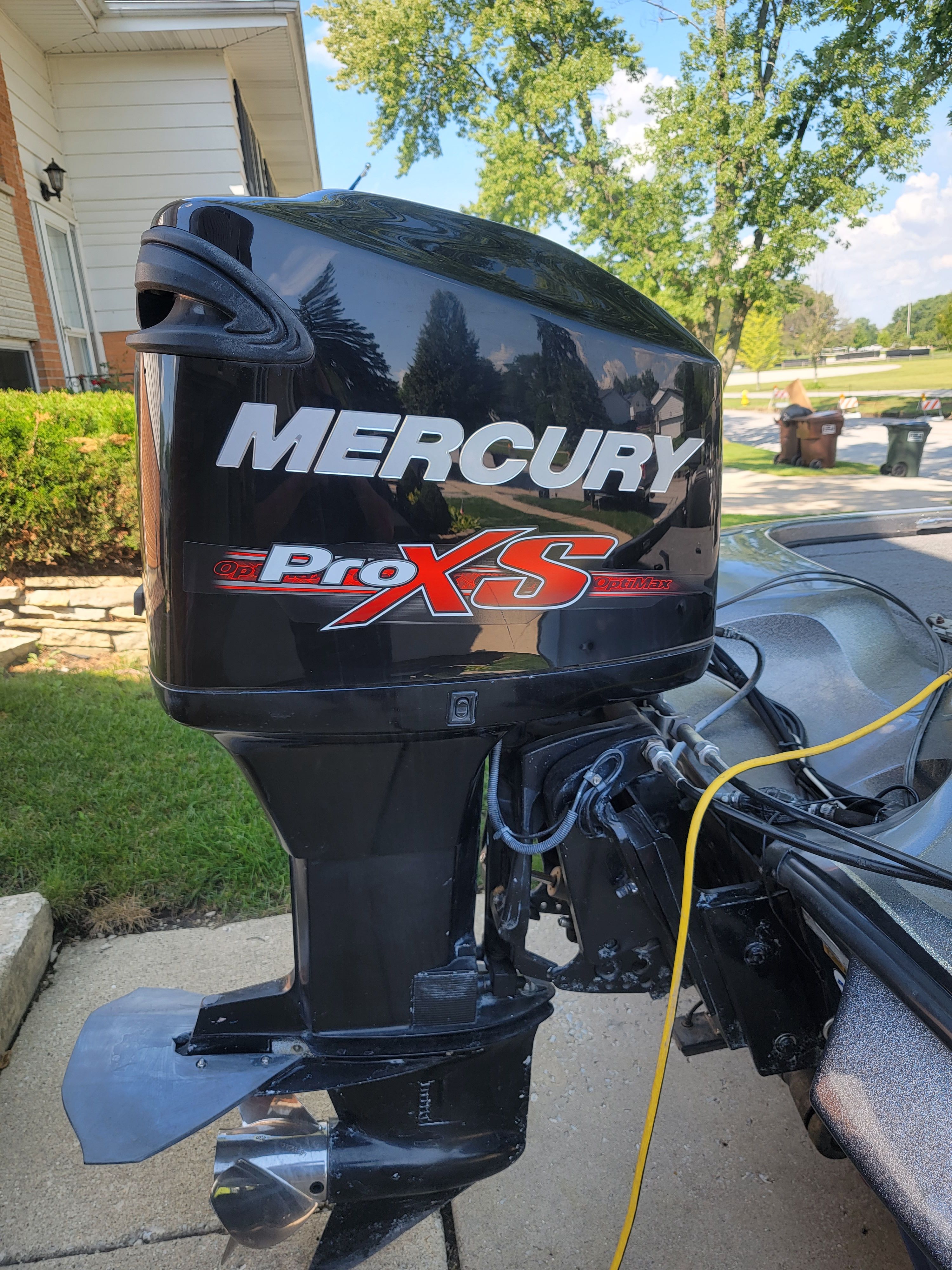 A Mercury Pro XS outboard motor on a boat parked on a paved area.