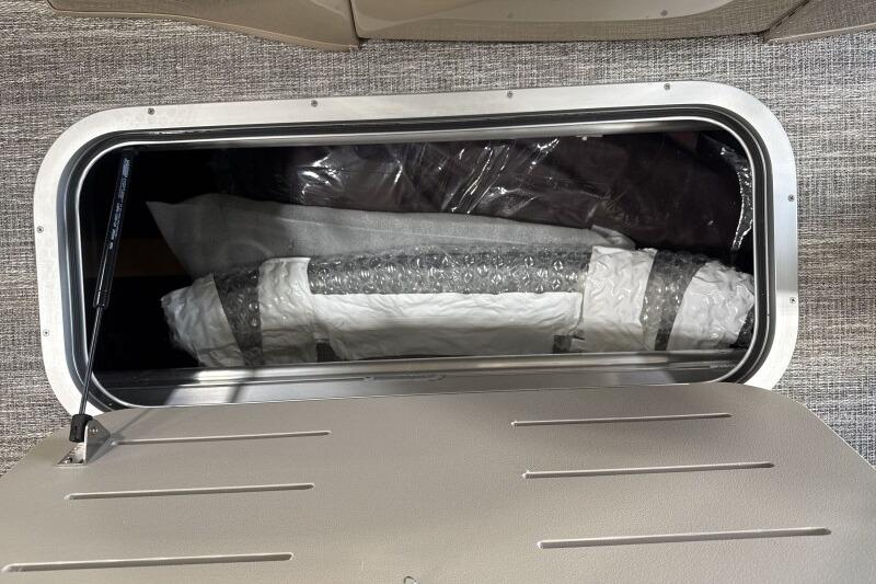 Storage compartment of 2026 Bennington 24 LXS Quadbench, showcasing interior space and materials.