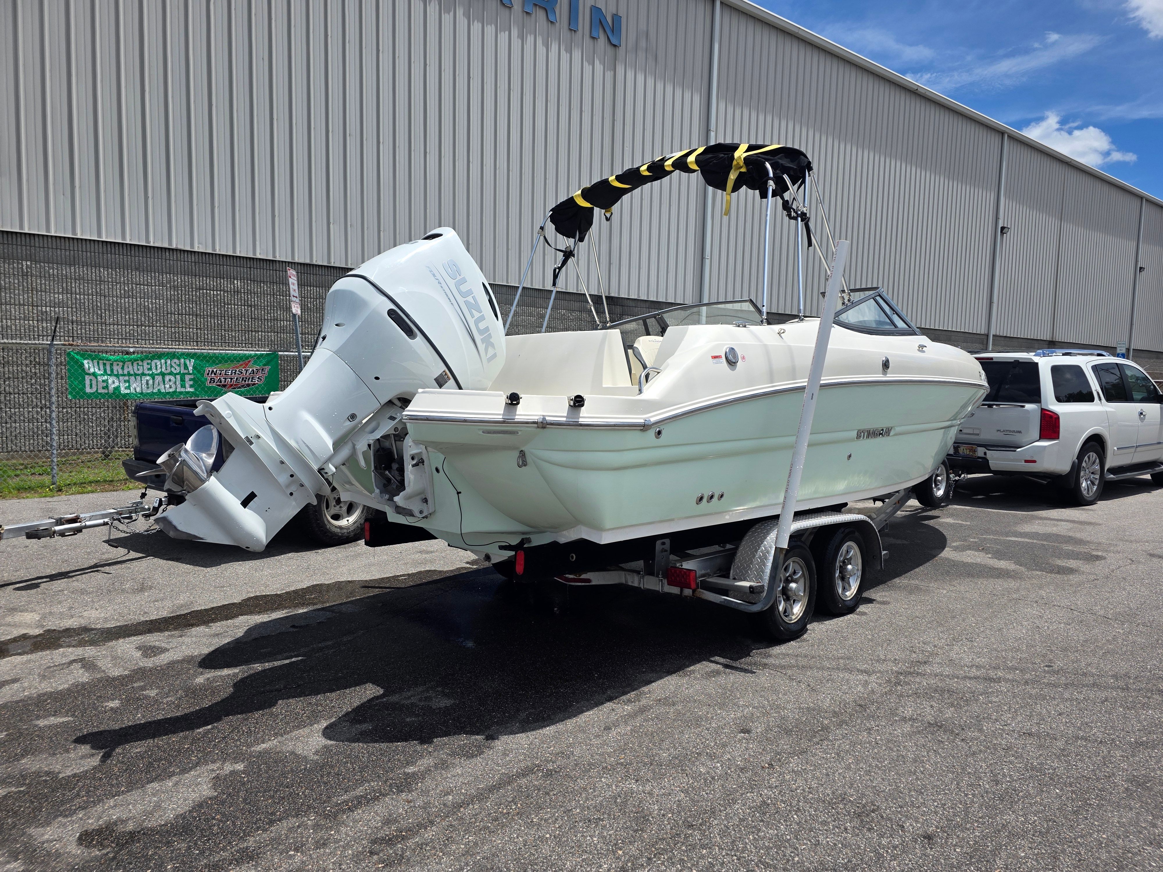 A white Stingray 231 DC boat on a trailer in front of a building.