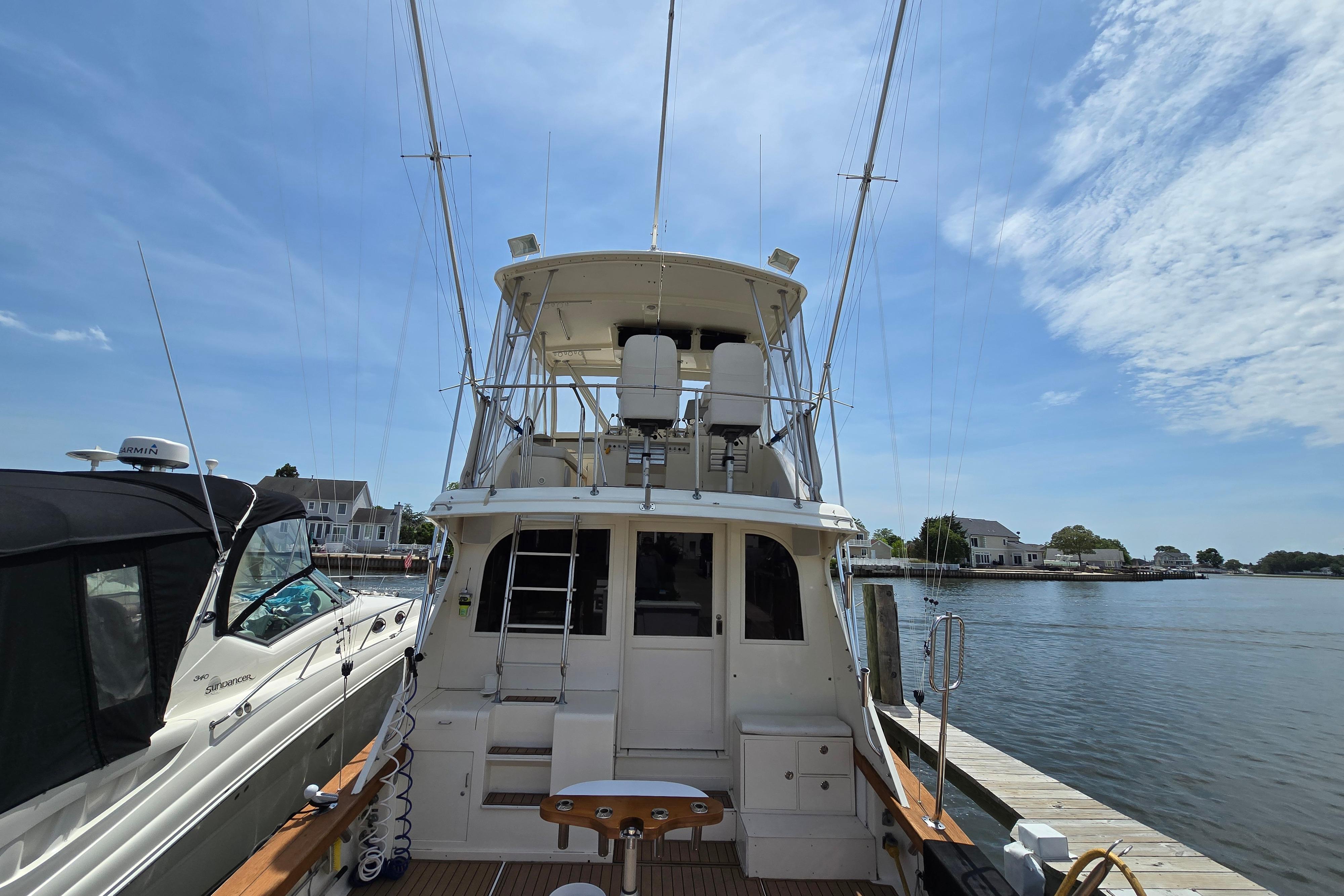 1988 Post 46 Convertible yacht docked by the water under a clear blue sky.