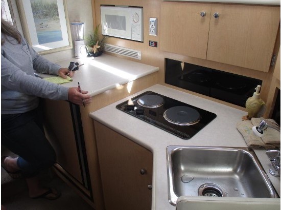 2000 Bayliner 3055 Ciera Sunbridge kitchen with stove, sink, and microwave.