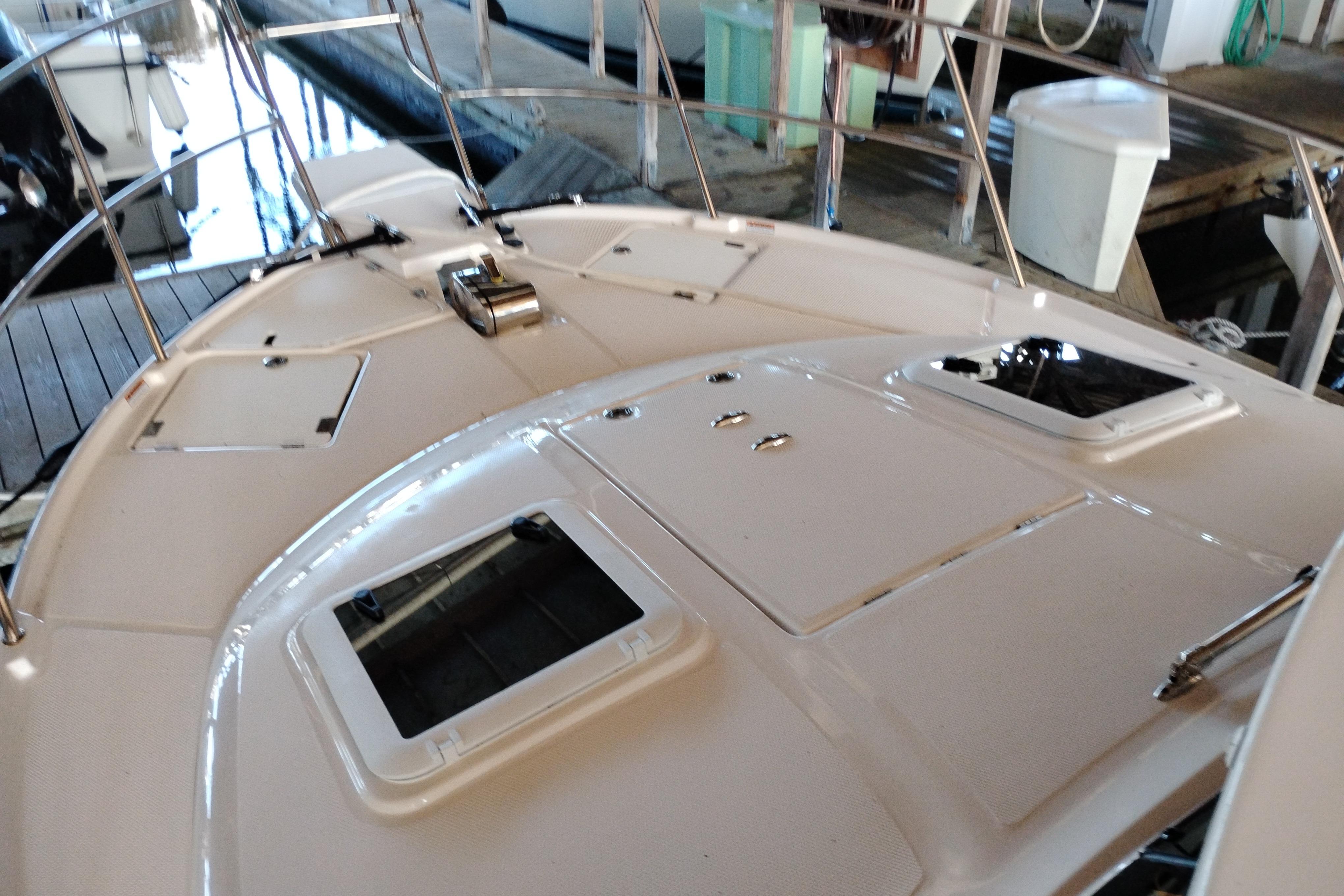 2022 Cutwater C-32 Coupe boat deck with hatches and railing in marina setting.