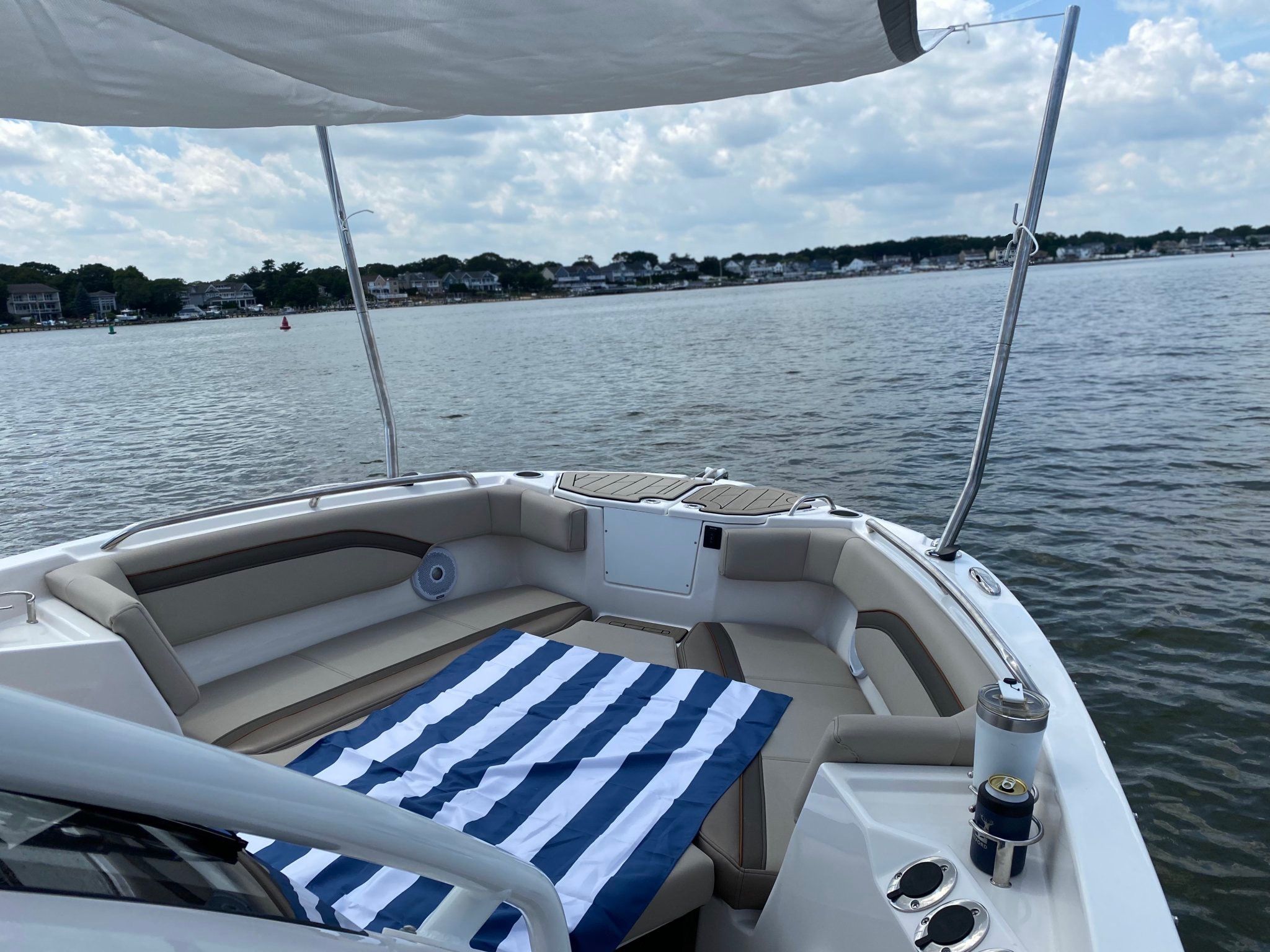 The boat features a comfortable seating area with a striped cushion, situated on calm water.