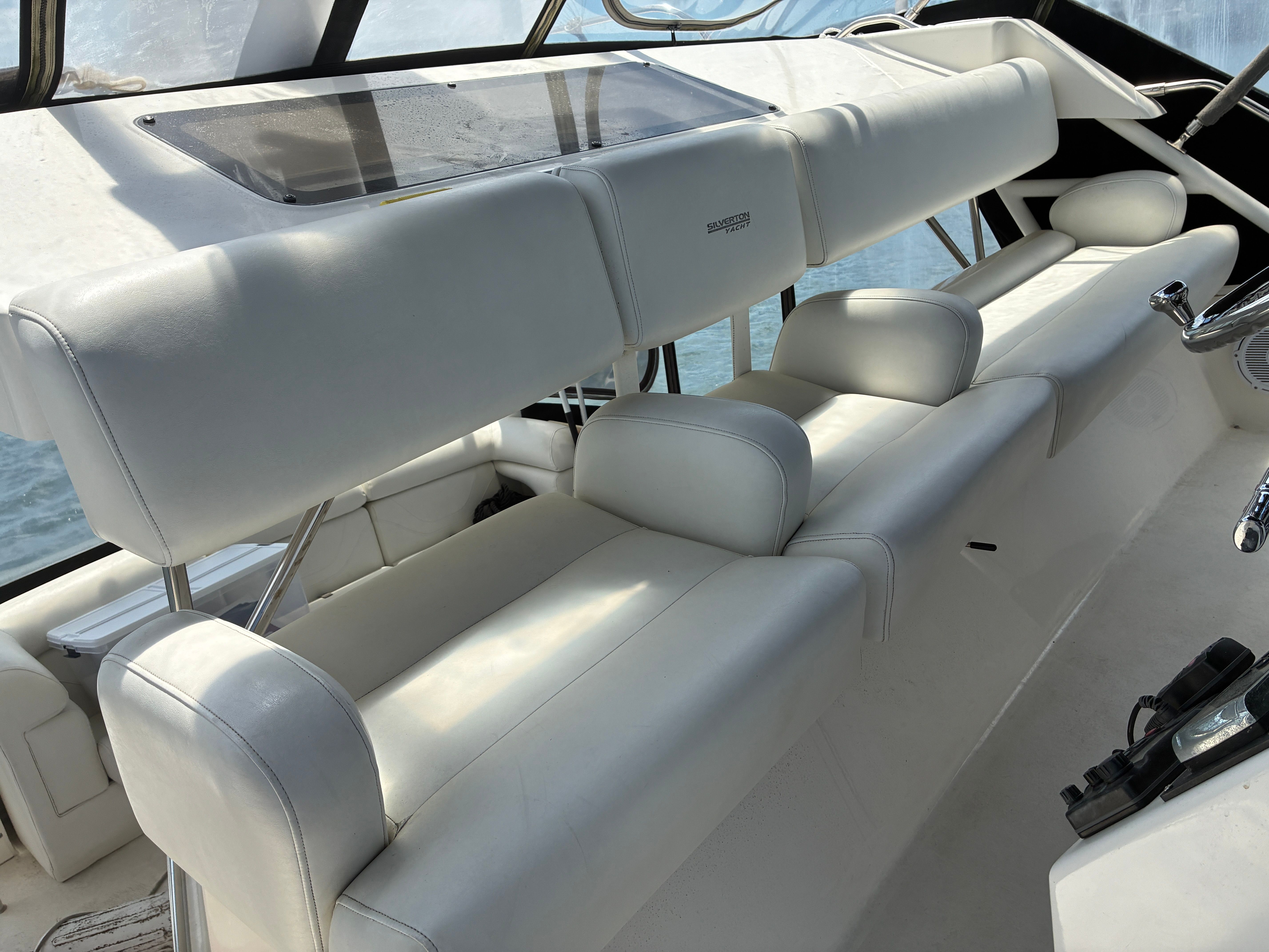 The image shows the cockpit of a 2001 Silverton 392 Motor Yacht with white leather seating.