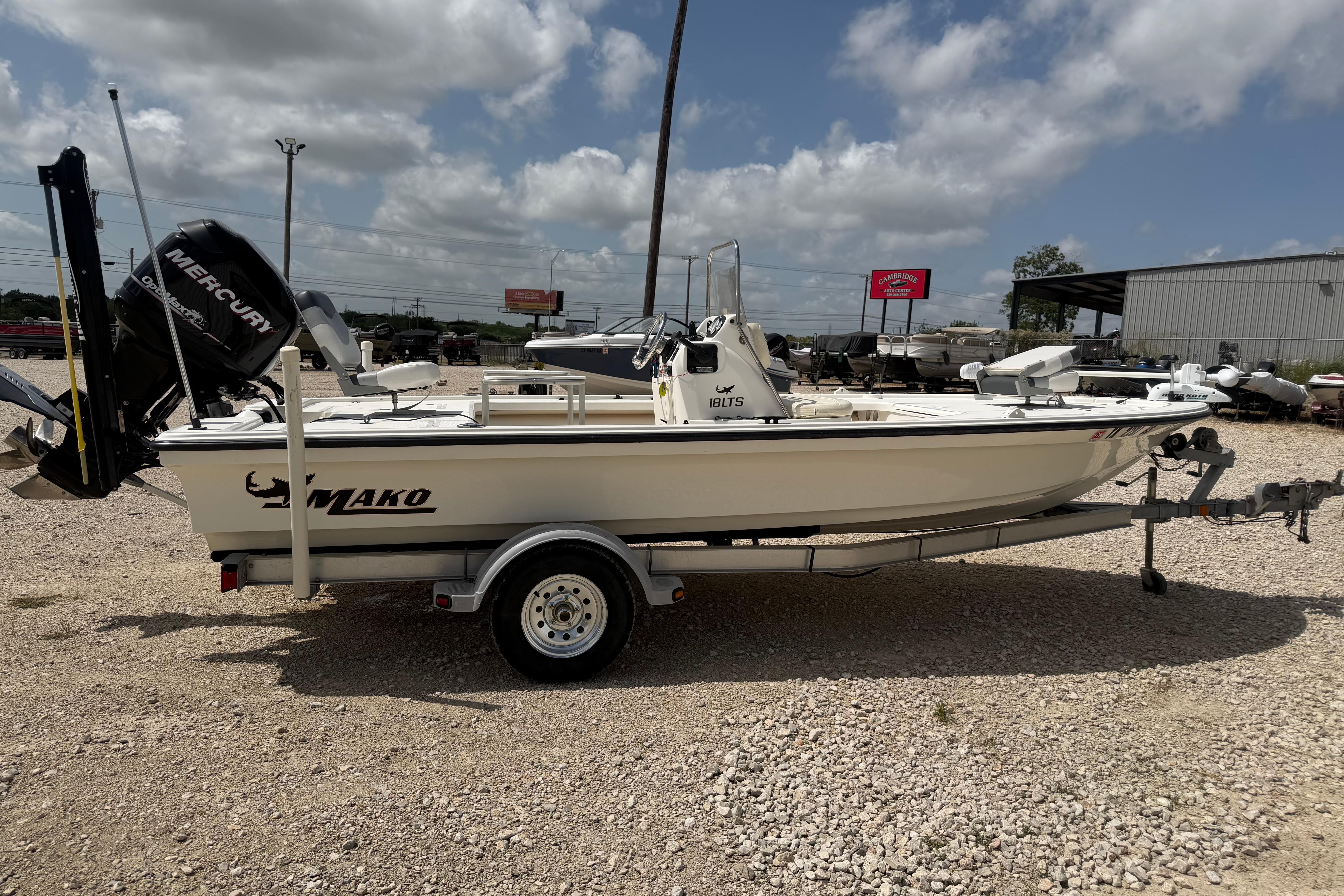 2012 Mako 18 LTS boat on trailer, parked outdoors under cloudy sky.