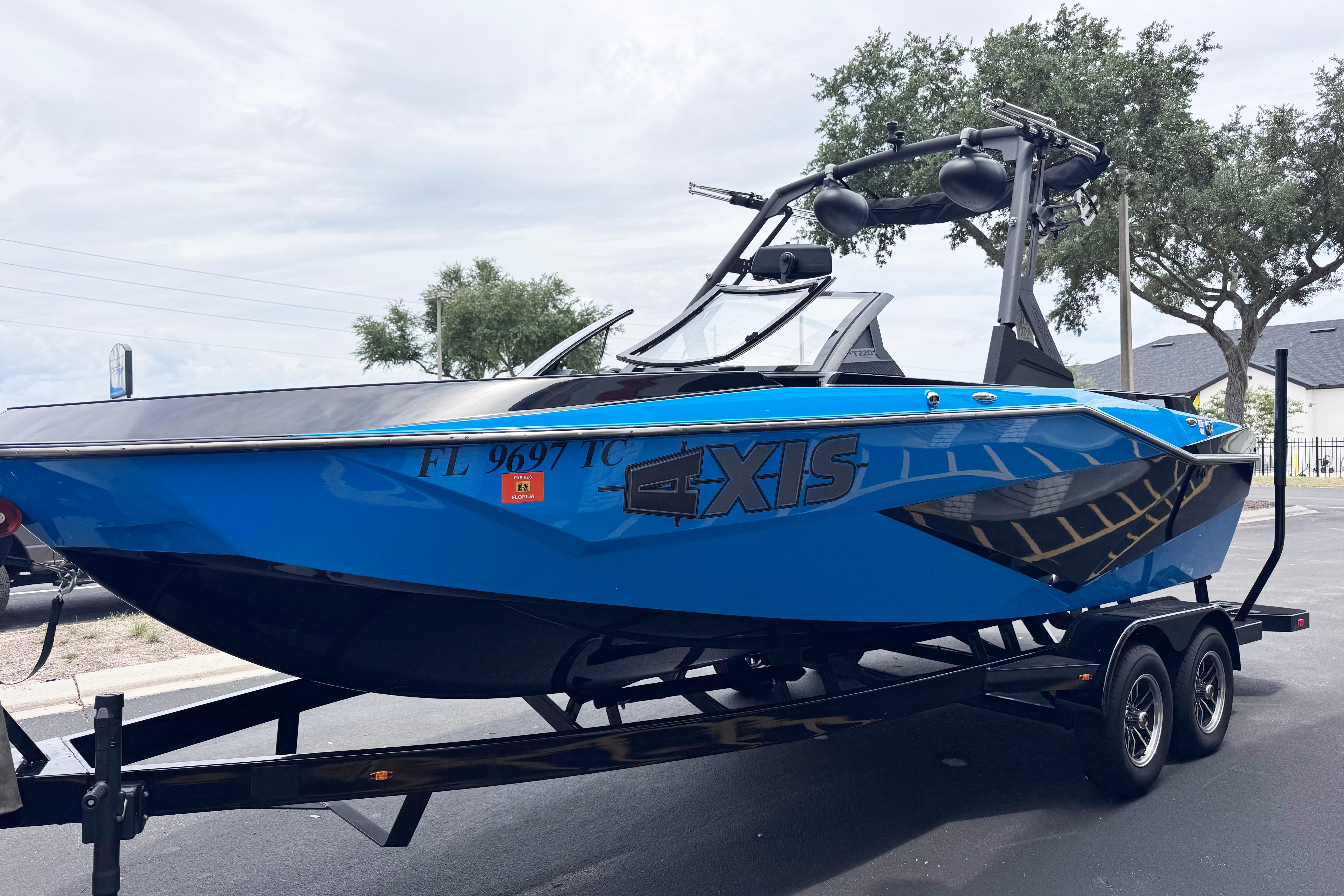 2022 Axis T220 boat in vibrant blue on a trailer, parked outdoors.
