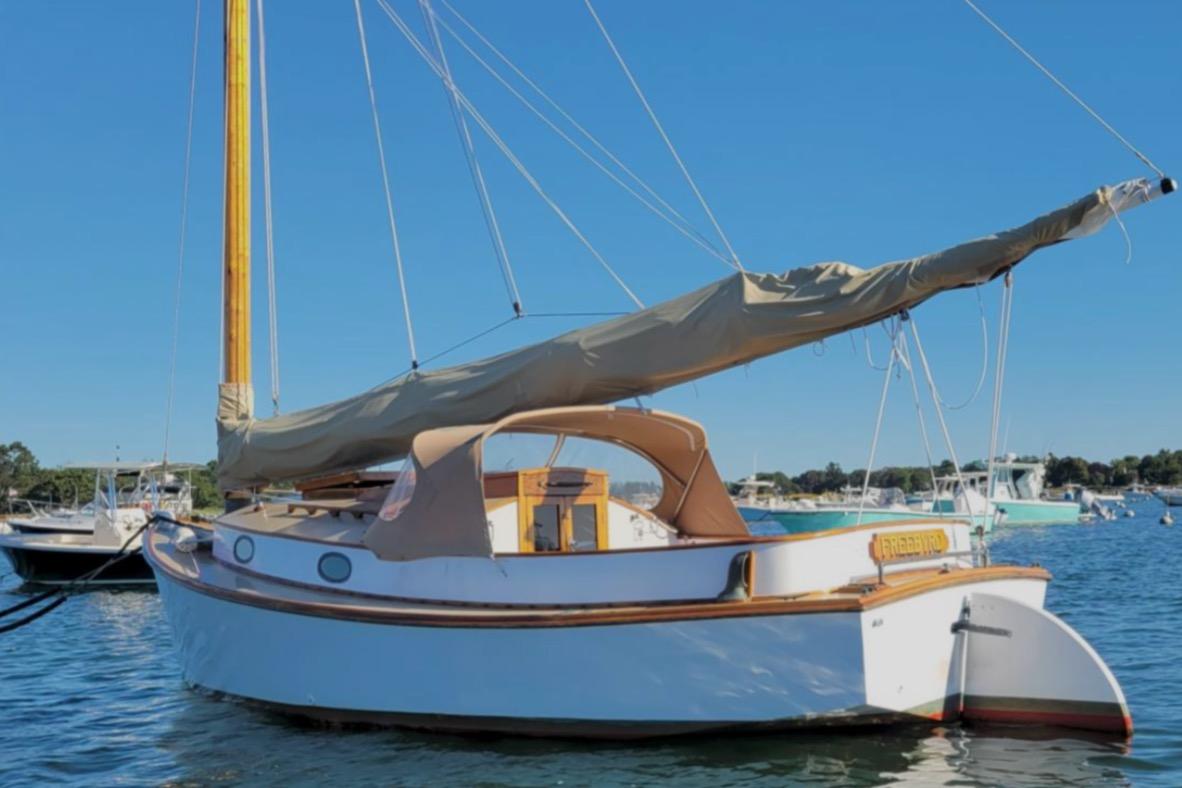 1978 Cape Cod Catboat, Ted Brewer model, anchored in a serene harbor setting.