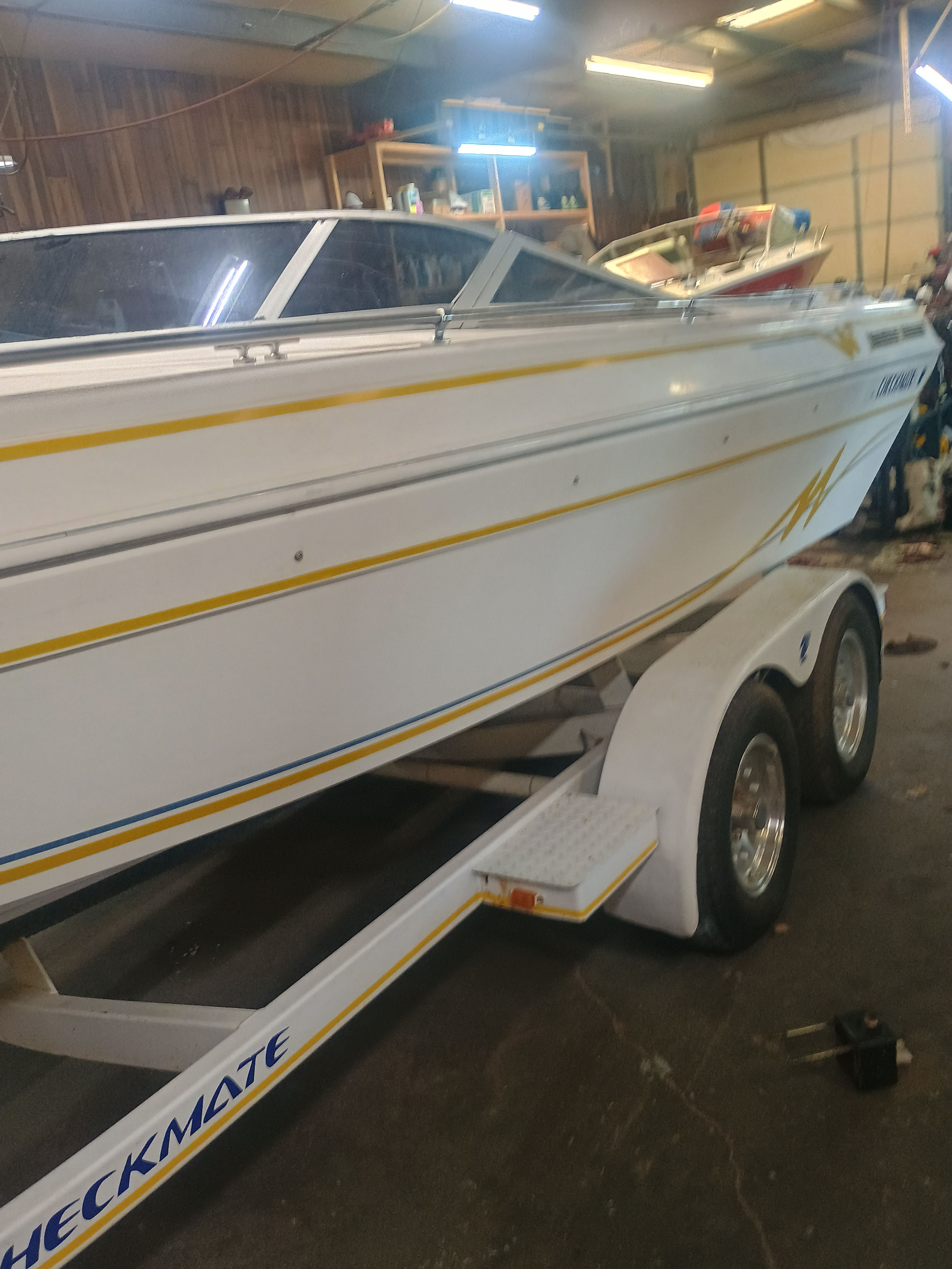 A white 1992 Checkmate 192 Persuader boat on a trailer in a garage.