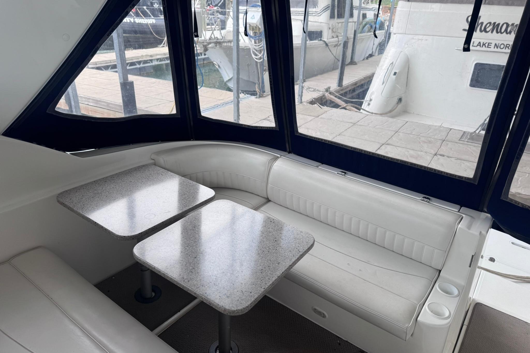 Interior of 2002 Cruisers Yachts 3275 Express with seating and tables, dockside view.