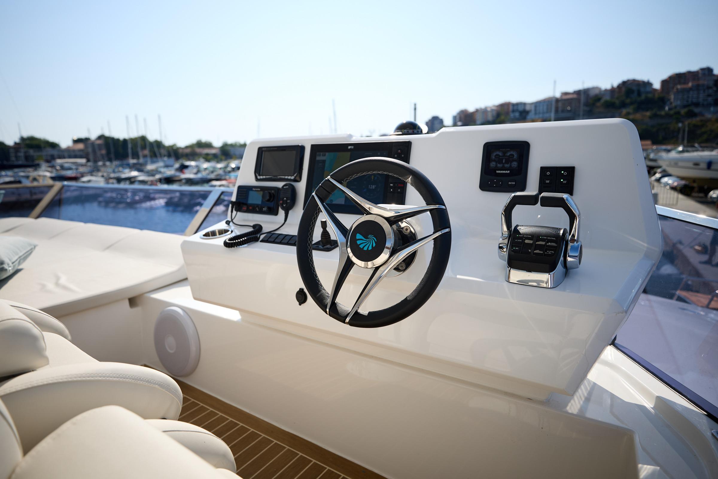 Steering console of 2025 Custom Omaya 50 Power Catamaran in marina setting.