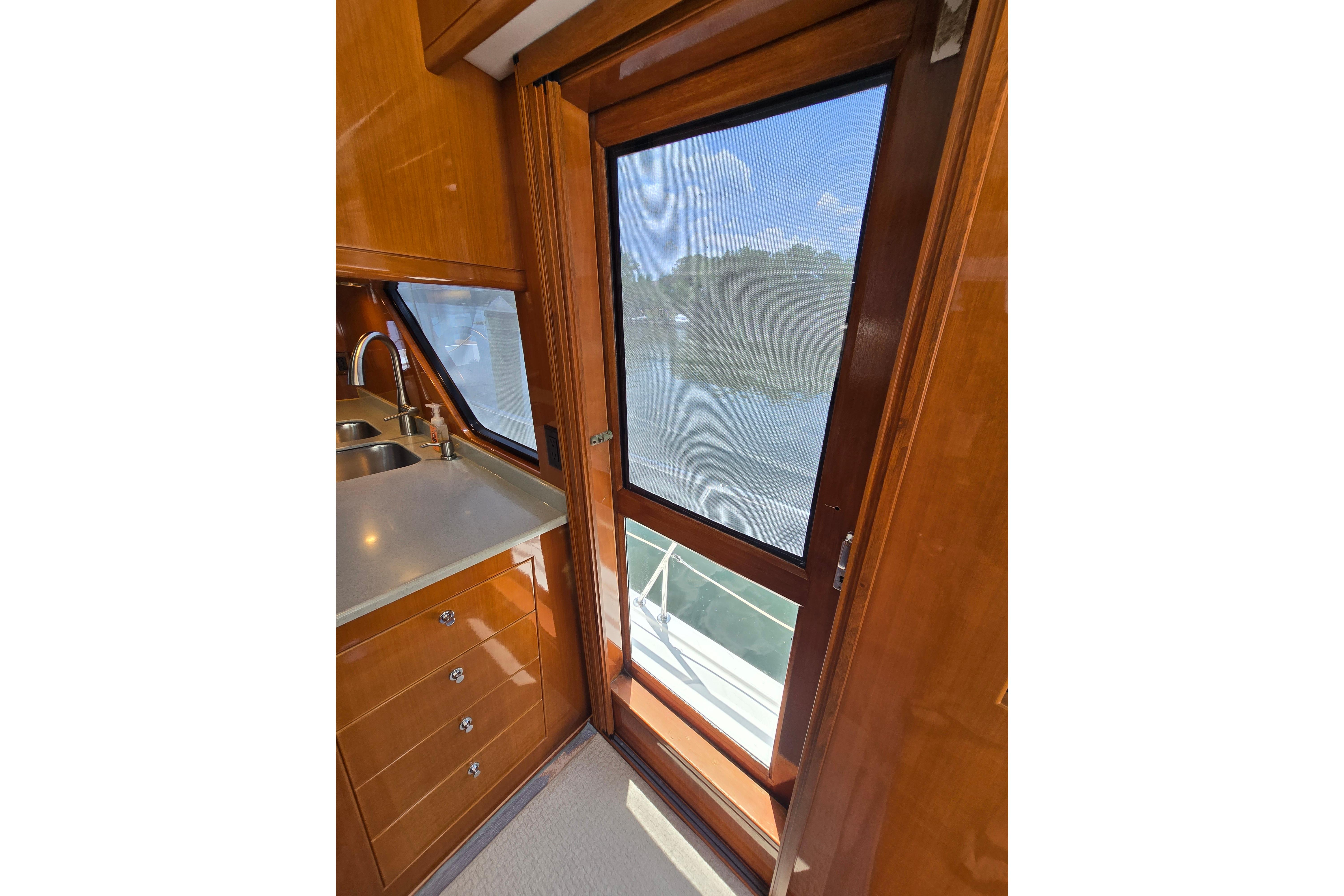 Interior view of 2004 Grand Harbour 58 yacht, featuring a sleek kitchen area with wooden cabinetry.