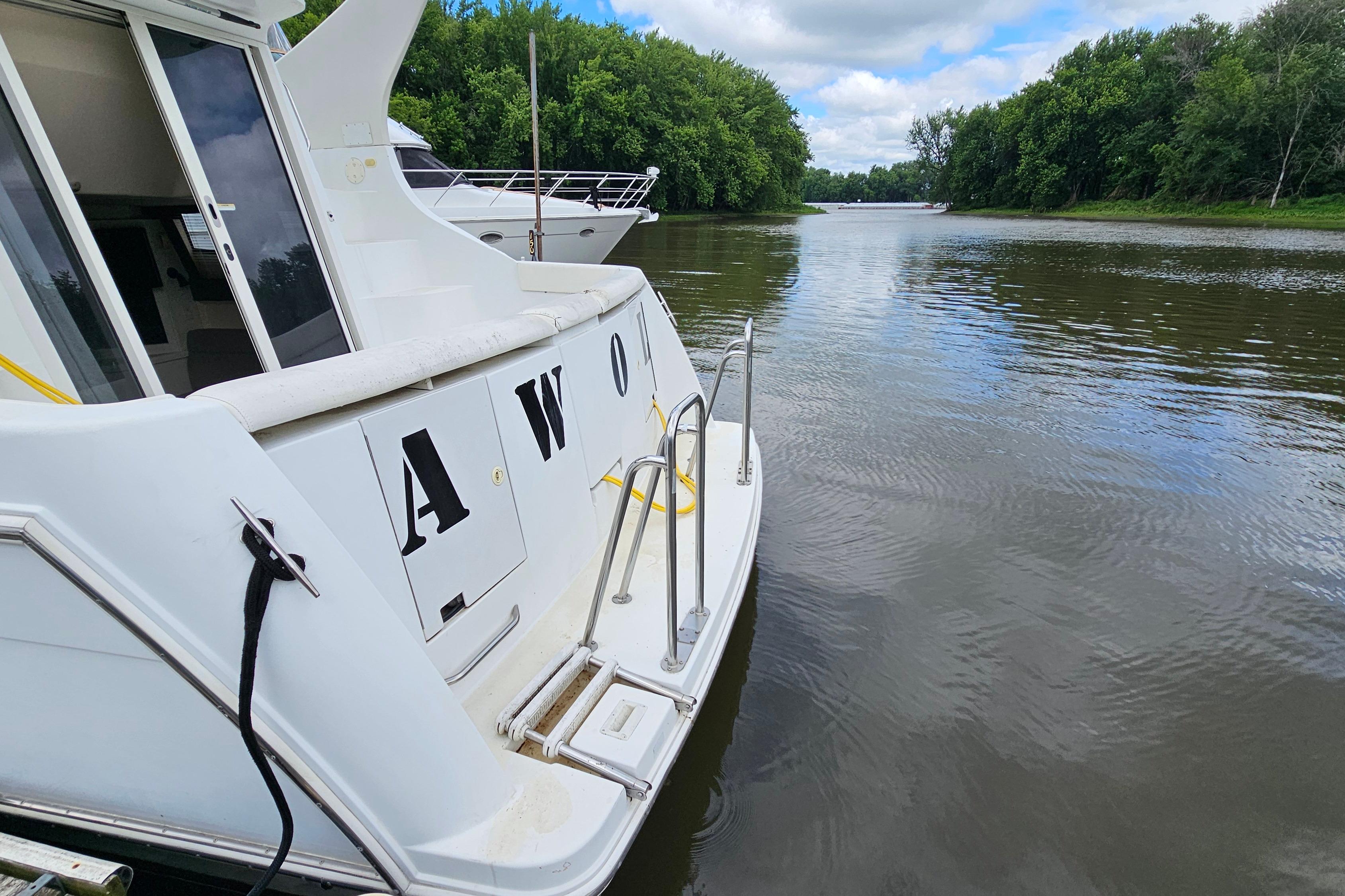 1999 Carver 350 Mariner yacht docked on a serene river with lush greenery.