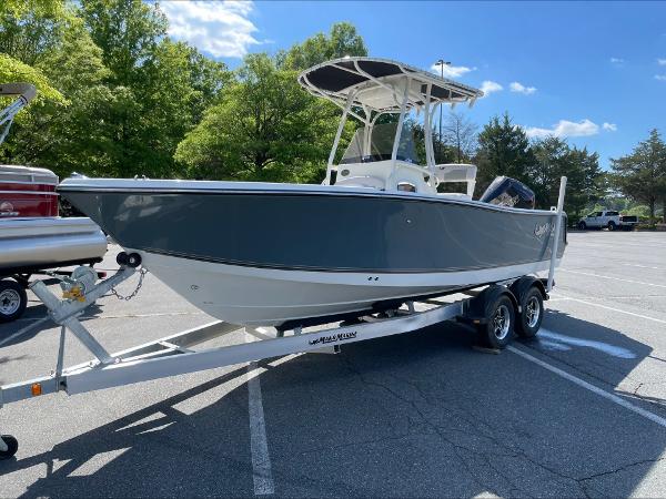 2024 Mako 214 CC boat on trailer in parking lot, sunny day, green trees in background.